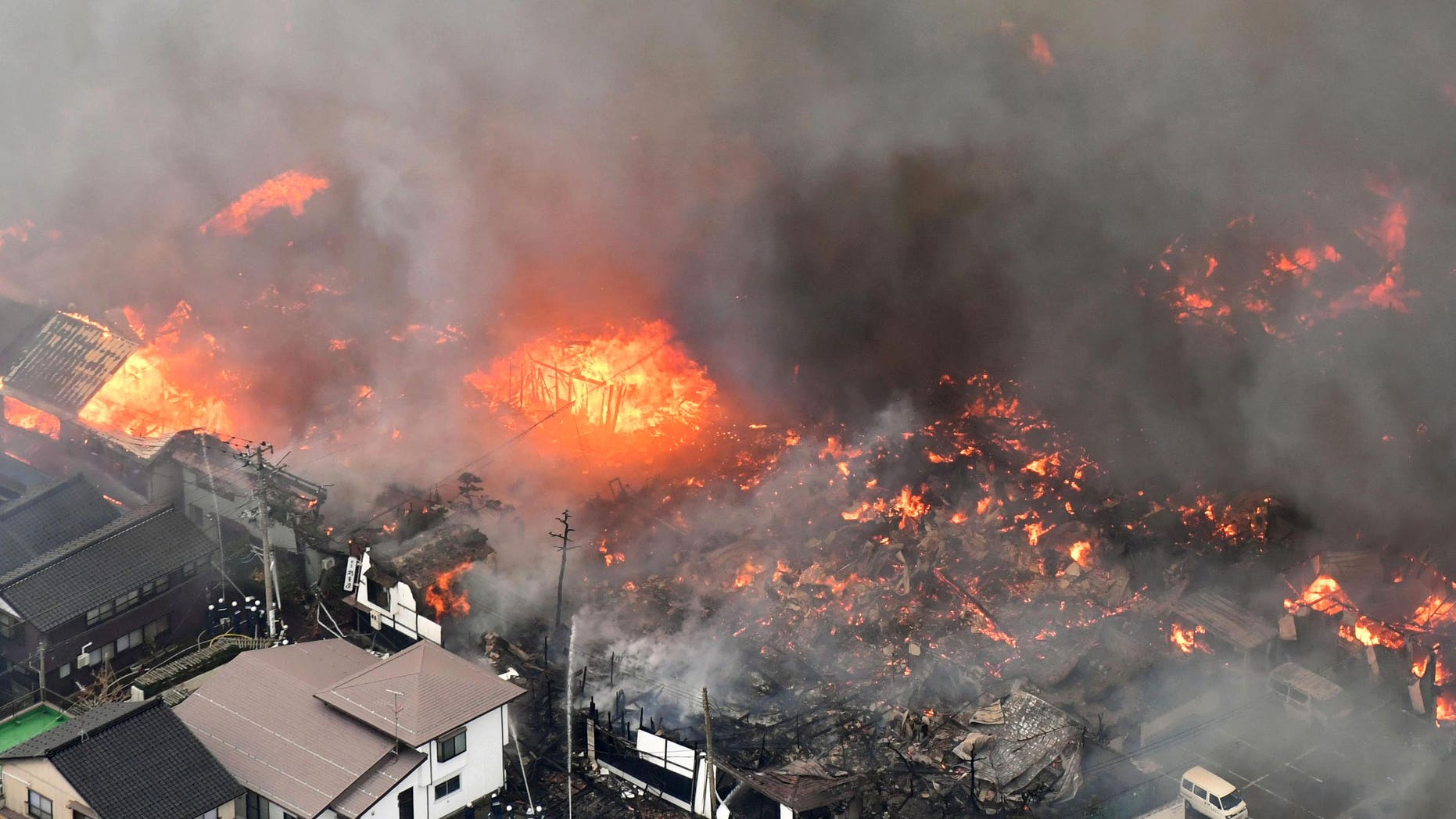 Smoke billow from houses during a fire in Itoigawa, northern Japan, Thursday, Dec. 22, 2016. A fire whipped by high winds has spread to at least 140 buildings in a small Japanese city on the Japan Sea coast. The fire department says the blaze started at a restaurant in Itoigawa city Thursday morning. By mid-afternoon, 140 houses and other buildings had caught fire, and the fire is still spreading. (Kyodo News via AP)