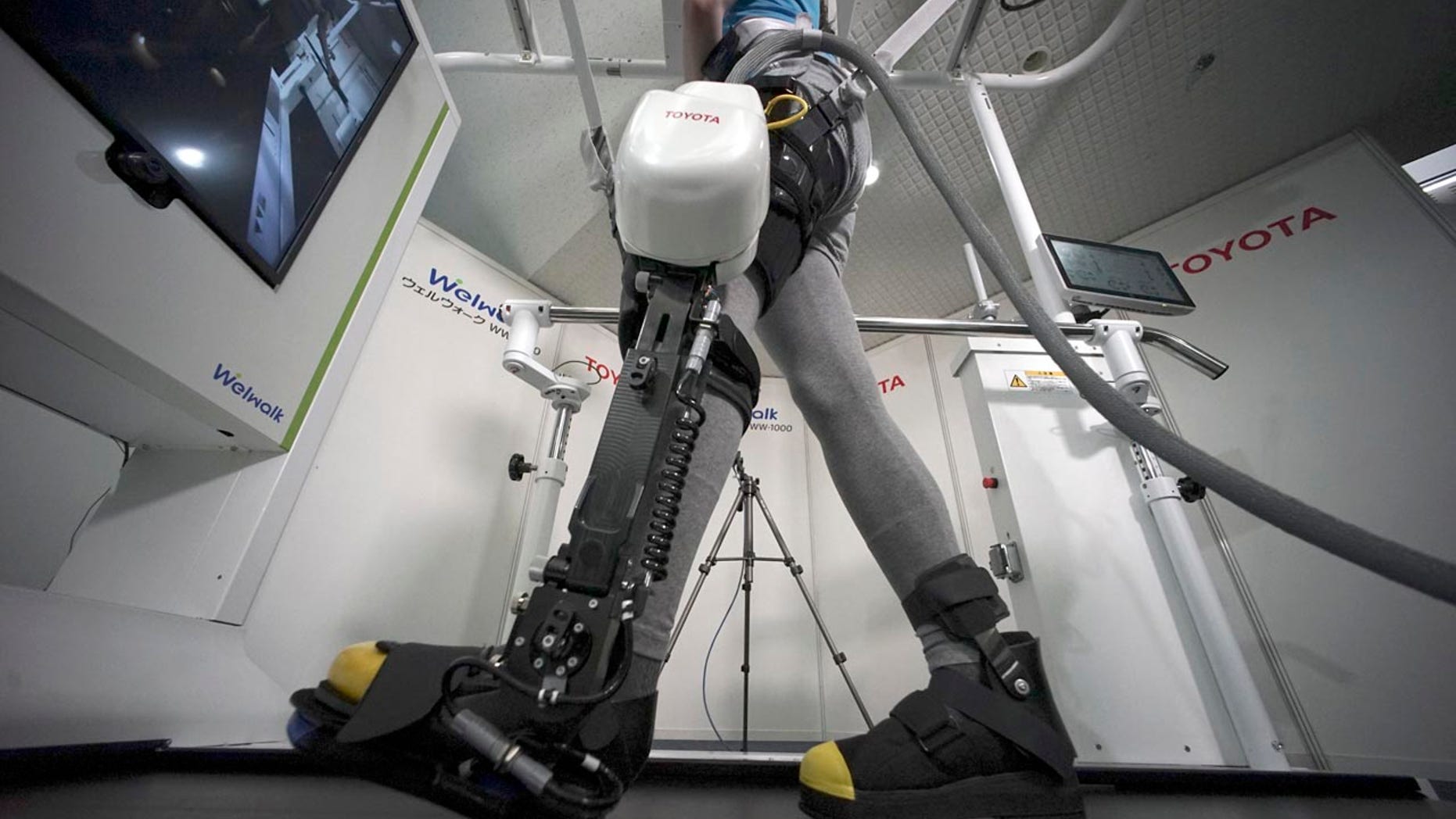 A model demonstrates the Welwalk WW-1000, a wearable robotic leg brace designed to help partially paralyzed people walk at the main system with treadmill and monitor, at Toyota Motor Corp.'s head office in Tokyo, Wednesday, April 12, 2017.