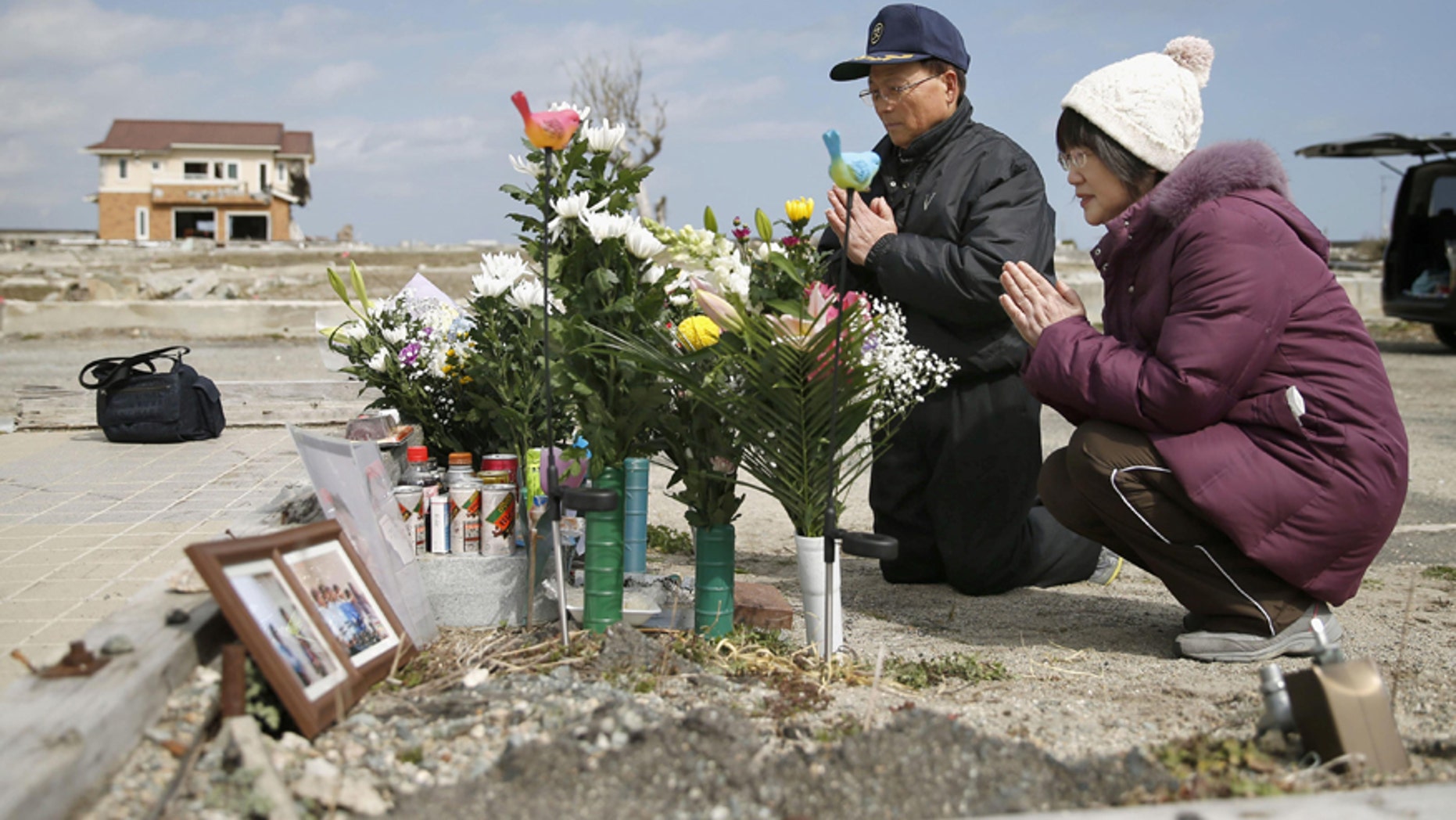 Tsutoshi Yoshida and his wife Seiko pray for their daughter who was killed by the 2011 tsunami, in Namie, Fukushima, northern Japan Friday, March 11, 2016. Japan on Friday marked the fifth anniversary of the 2011 tsunami that killed more than 18,000 people and left a devastated coastline along the country's northeast that has still not been fully rebuild. (Hironori Asakawa/Kyodo News via AP) JAPAN OUT, MANDATORY CREDIT