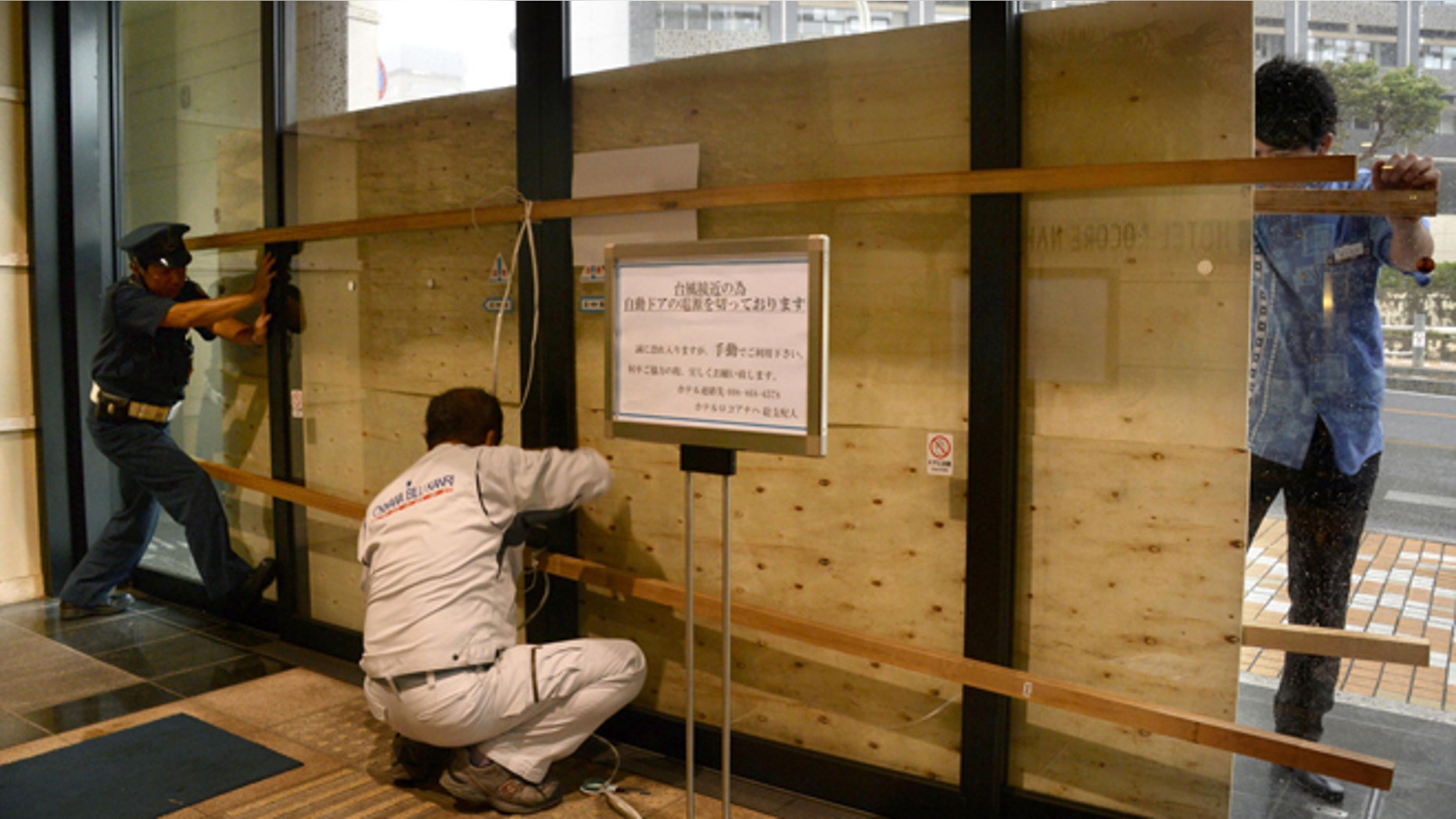 Oct. 11, 2014: Hotel employees and a guard secure its entrance door with a plywood board in preparation for approaching typhoon Vongfong in Naha, Okinawa.