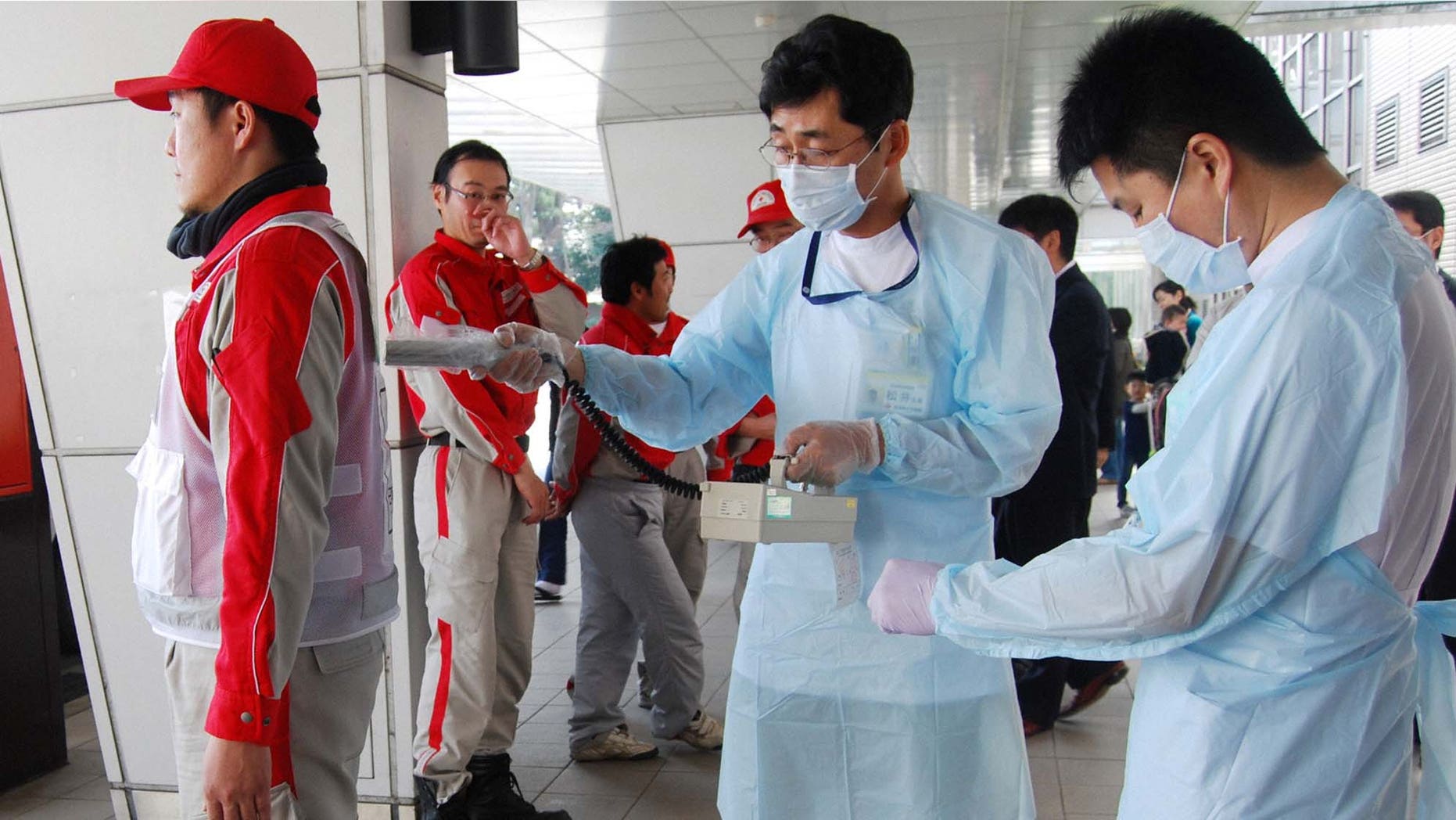 March 14: A Red Cross rescue worker, in red, is scanned for signs of radiation upon returning from Fukushima to his hospital in Nagahama, Shiga Prefecture.