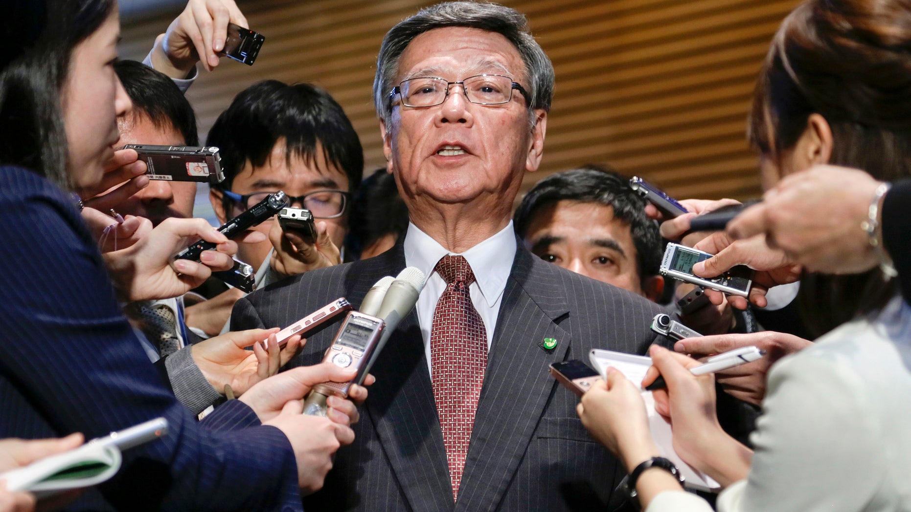 FILE - In this March 4, 2016 file photo, Okinawa Gov. Takeshi Onaga is surrounded by reporters after a meeting with Japanese Prime Minister Shinzo Abe at the latter's official residence in Tokyo. Japan and the U.S. have marked a partial return of the land used by American troops to Okinawa in a ceremony on the southern island Thursday, Dec. 22, 2016, , but there was no sign the move was helping to lessen protests against the heavy U.S. military presence. Demanding an unconditional land return, Okinawa Gov. Onaga skipped Thursdays ceremony and joined a protest. (Kimimasa Mayama/Pool Photo via AP, File)