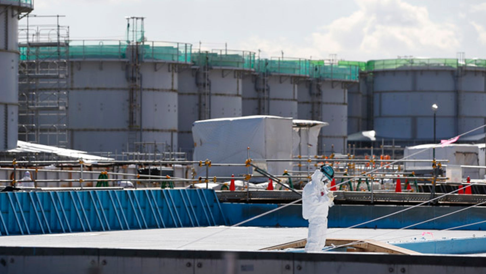 FILE 2016: A worker, wearing protective suits and masks, takes notes in front of storage tanks for radioactive water at the tsunami-crippled Fukushima Dai-ichi nuclear power plant, operated by Tokyo Electric Power Co. (TEPCO), in Okuma, Fukushima Prefecture, northeastern Japan.