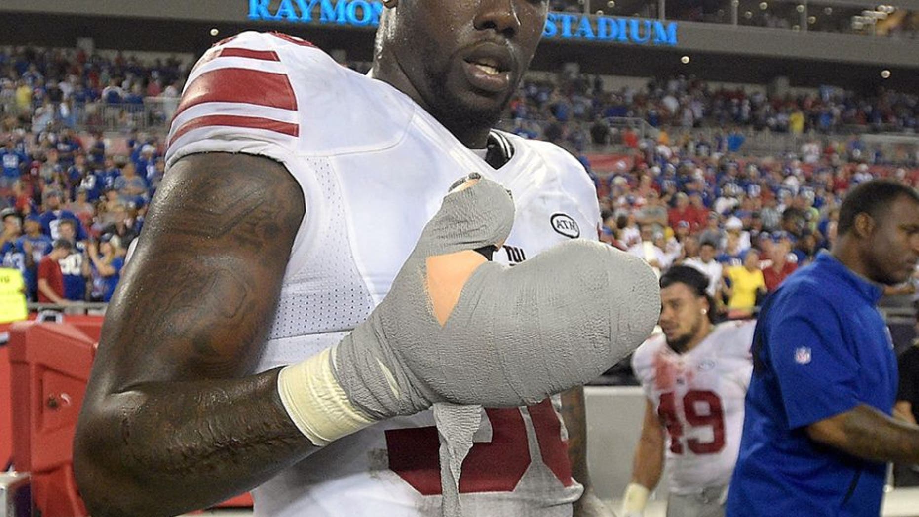 New York Giants defensive end Jason Pierre-Paul removes the bandage from his damaged hand after the Giants defeated the Tampa Bay Buccaneers 32-18 during an NFL football game Sunday, Nov. 8, 2015, in Tampa, Fla. (AP Photo/Phelan M. Ebenhack)