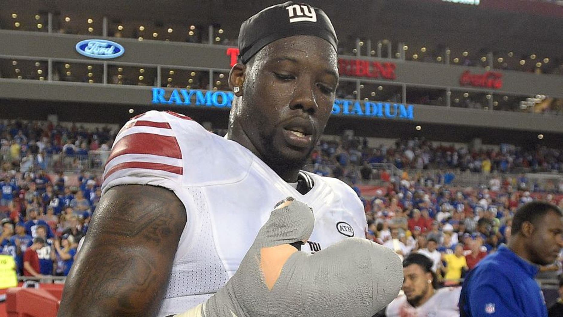 New York Giants defensive end Jason Pierre-Paul removes the bandage from his damaged hand after the Giants defeated the Tampa Bay Buccaneers 32-18 during an NFL football game Sunday, Nov. 8, 2015, in Tampa, Fla. (AP Photo/Phelan M. Ebenhack)