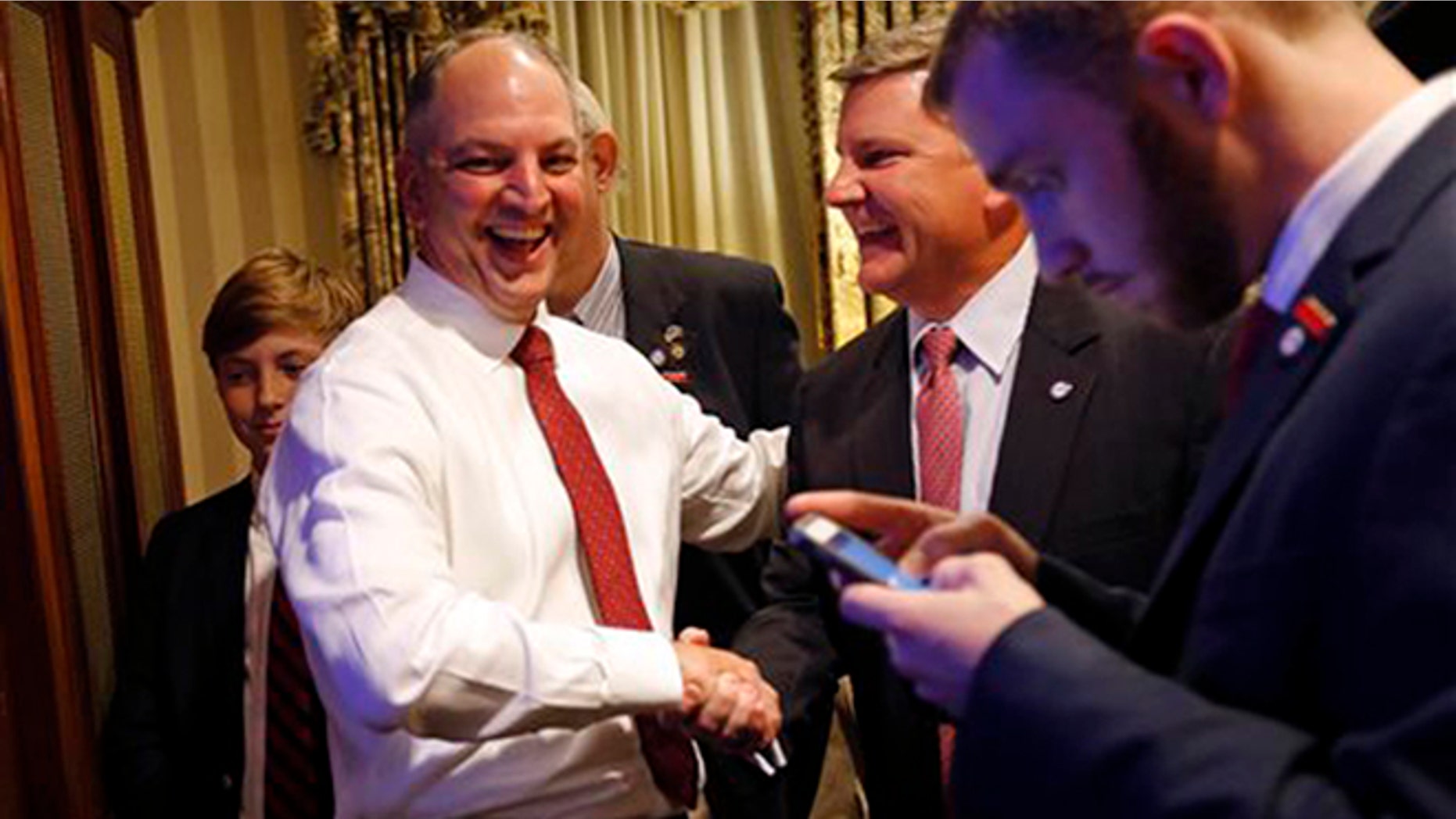 Louisiana Democratic gubernatorial candidate Rep. John Bel Edwards greets supporters as he watches election returns in a hotel suite at his election night watch party in New Orleans, Saturday, Nov. 21, 2015.