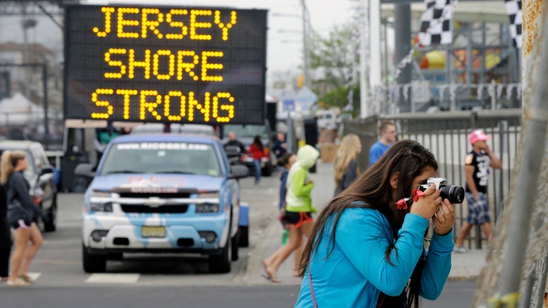 May 18, 2013: Angelina Zuzuro, 16, of Denville, takes photos near a sign in Seaside Heights, N.J.. The boardwalks are back, and so are most of the beaches, even if some are a little thinner this year. The smell of funnel cakes, french fries and pizza will mingle with the salt air, and the screech of seagulls will be heard. But so will the thwack of hammers repairing what can be fixed and the roar of bulldozers and backhoes tearing down what cant. Welcome to Summer 2013 at the Jersey shore, the first since Superstorm Sandy pummeled the coast and upended hundreds of thousands of lives. (AP/Mel Evans)
