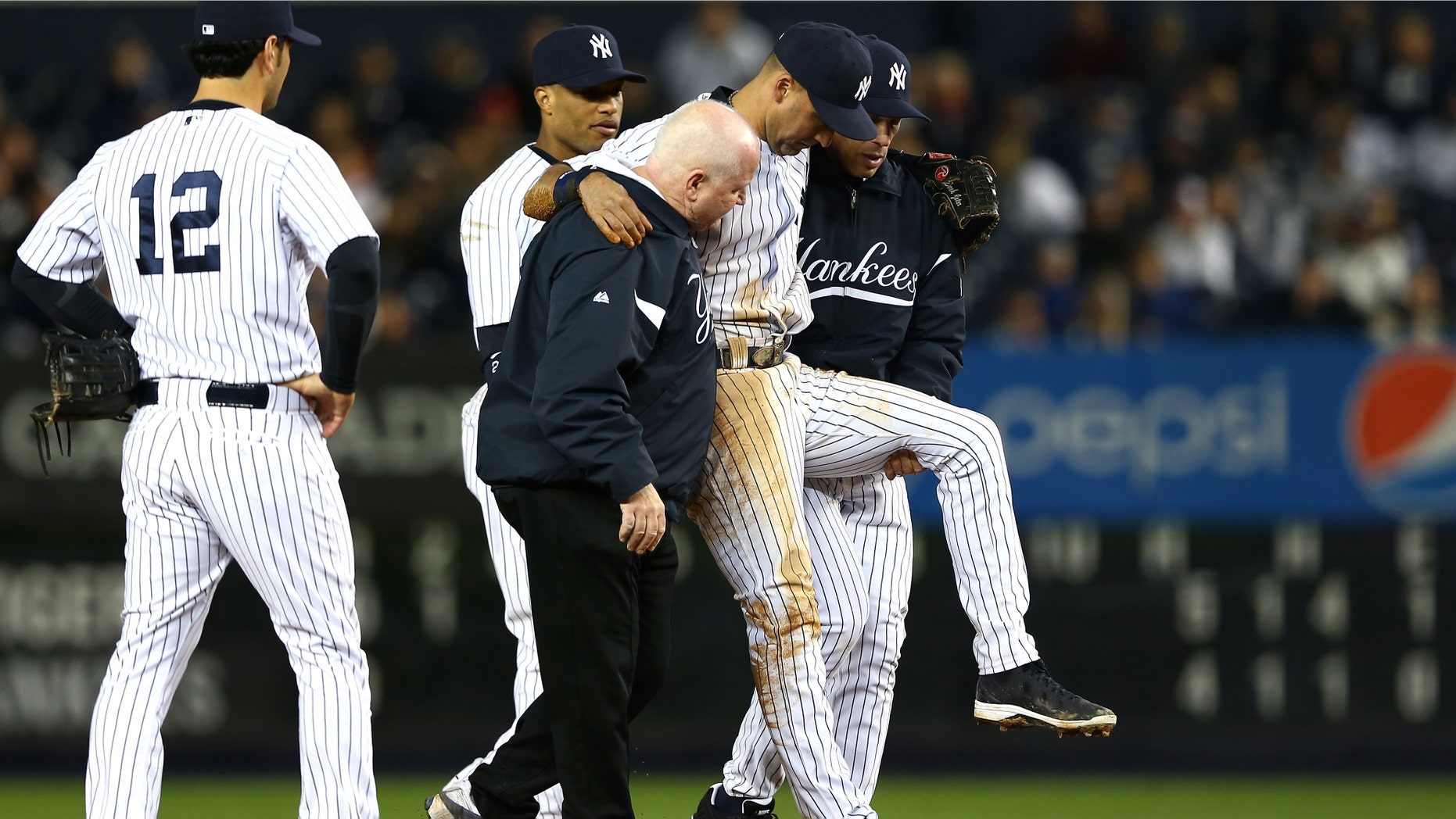 NEW YORK, NY - OCTOBER 13: Derek Jeter #2 of the New York Yankees is carried off of the field by trainer Steve Donohue and manager Joe Girardi after Jeter injured his leg in the top of the 12th inning against the Detroit Tigers during Game One of the American League Championship Series at Yankee Stadium on October 13, 2012 in the Bronx borough of New York City, New York. (Photo by Elsa/Getty Images)
