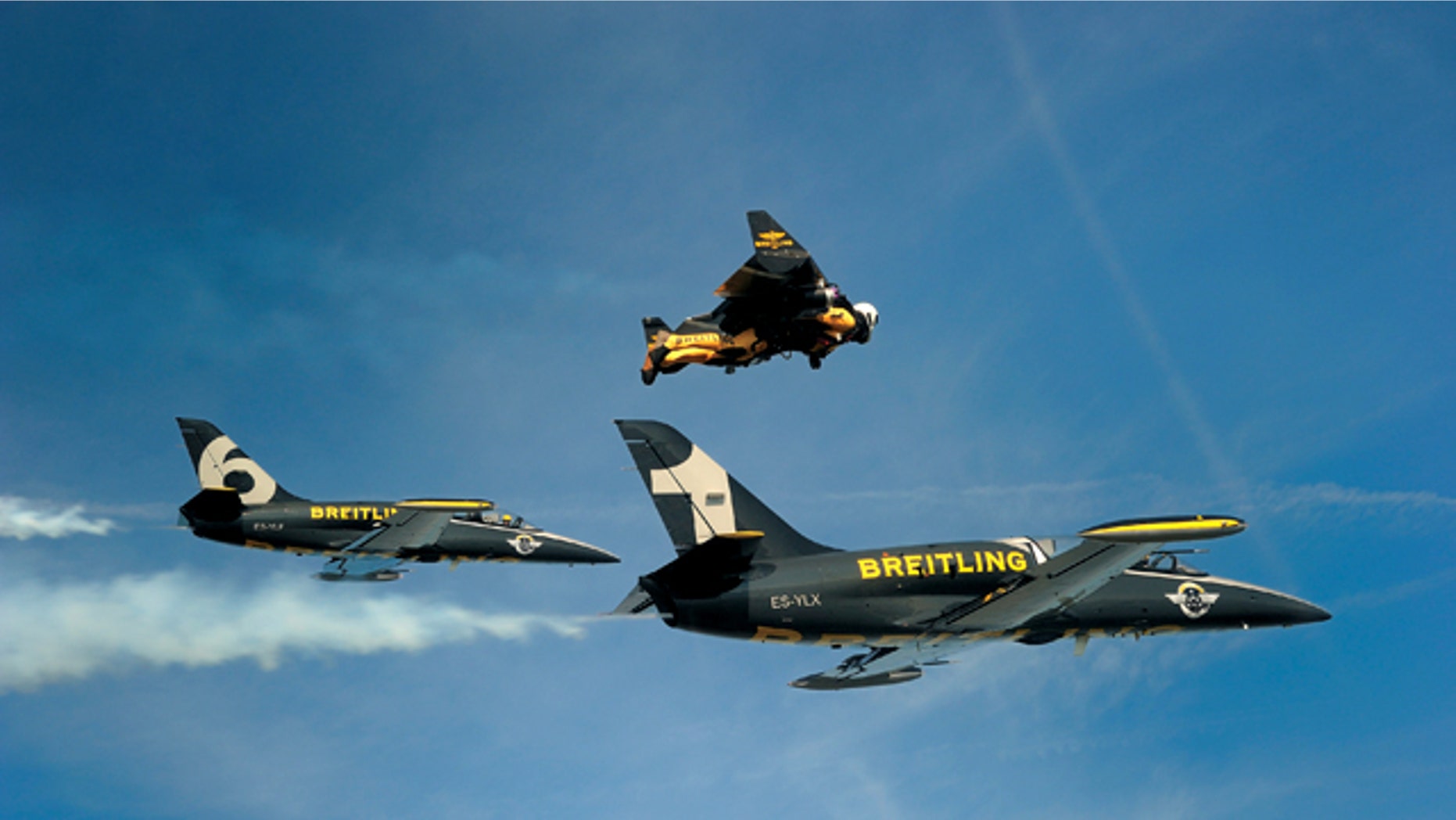 Jetman Yves Rossy flies in his custom wingsuit alogside a pair of Swiss air force jets.