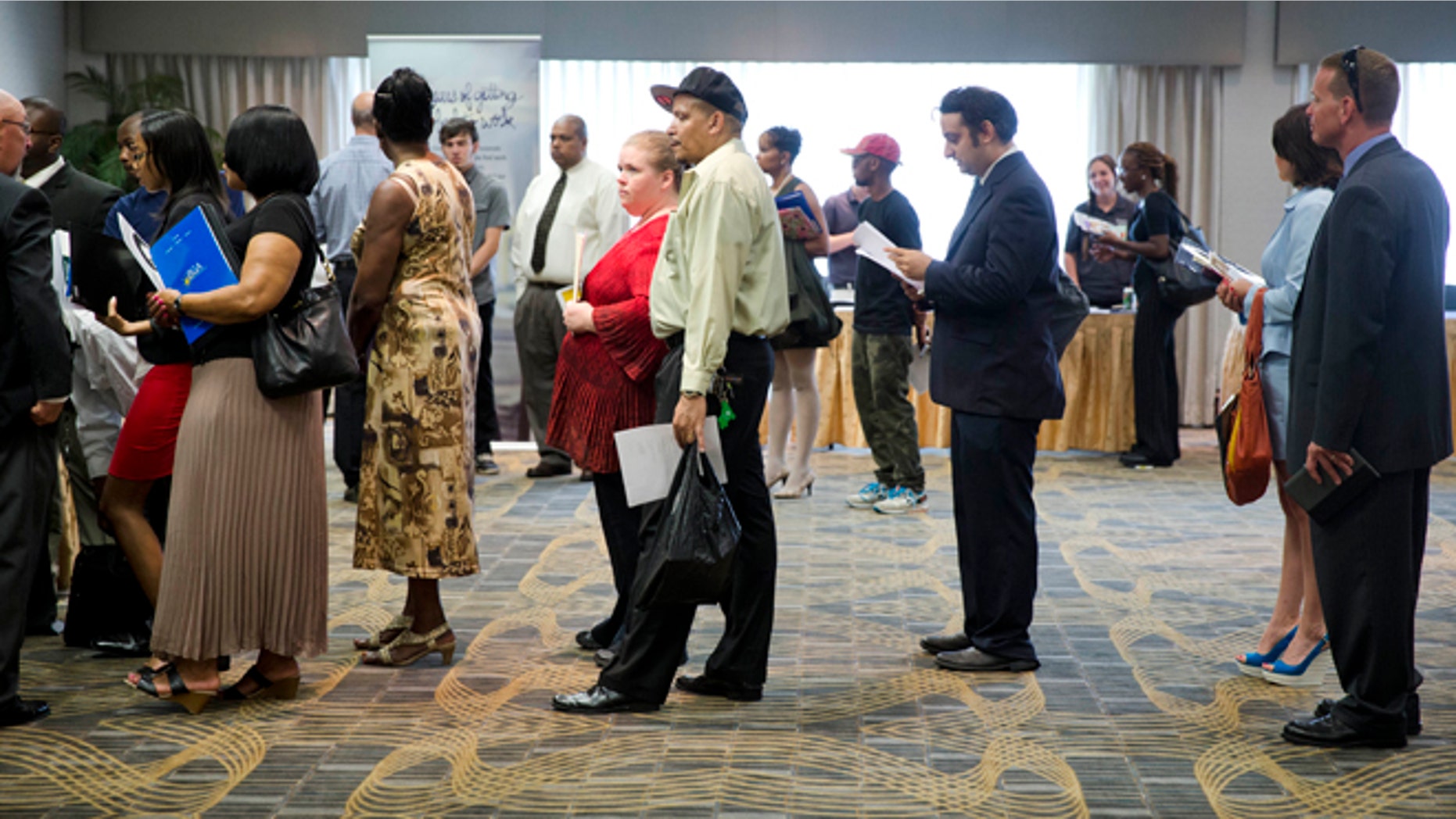 In this June 23, 2014 photo, people wait in line to meet with recruiters during a job fair in Philadelphia.