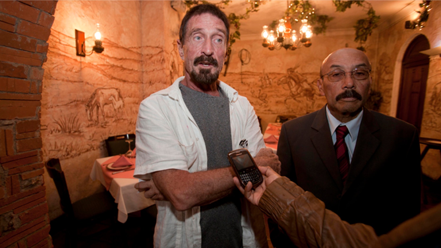 Dec. 4, 2012: Software company founder John McAfee, left, accompanied by his lawyer Telesforo Guerra, right, answers questions during an interview at a local restaurant in Guatemala City.
