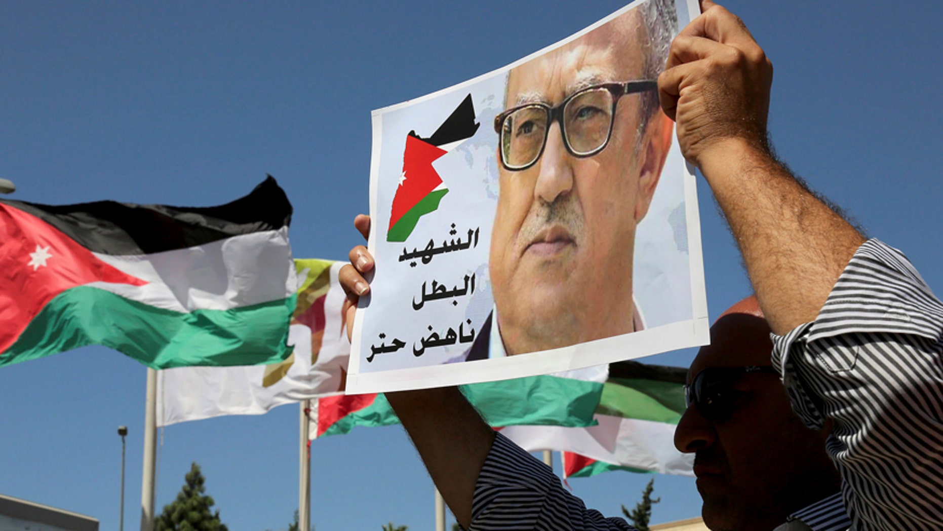 FILE - In this Monday, Sept. 26, 2016, file photo, relatives of Jordanian writer Nahed Hattar hold up signs protesting his death, in front of Jordanian Prime Ministry in Amman, Jordan. Nahad Hattar, the writer, had been on trial for posting a cartoon deemed offensive to Islam on social media when an assailant killed him outside the courthouse. The shooter was a former mosque prayer leader motivated by anger over the cartoon, officials said at the time. (AP Photo/Raad Adayleh)