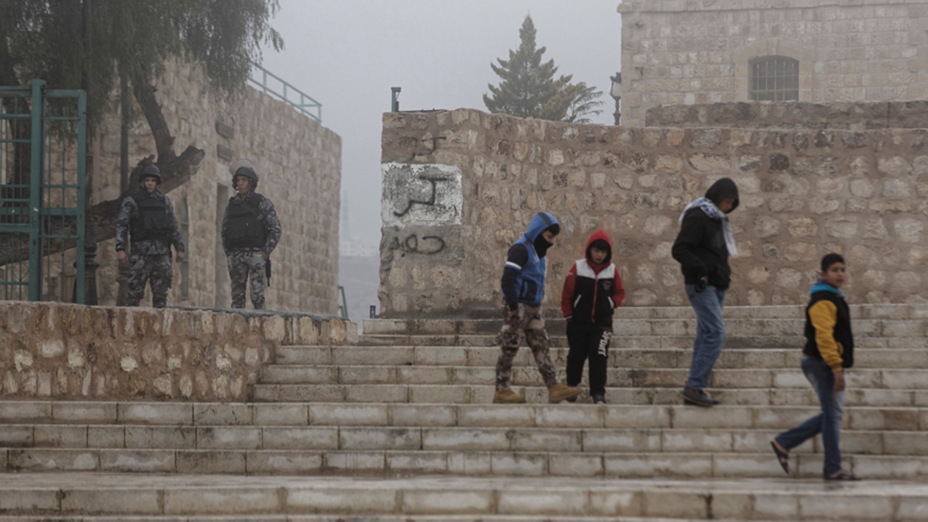 Jordanian security forces guard an entrance, left, as boys walk past in the morning mist in front of Karak Castle in the central town of Karak, about 140 kilometers (87 miles) south of the capital Amman, in Jordan Monday, Dec. 19, 2016. Gunmen assaulted Jordanian police in a series of attacks Sunday, including at the Karak Crusader castle popular with tourists, killing seven officers, two local civilians and a woman visiting from Canada, officials said. (AP Photo/Ben Curtis)