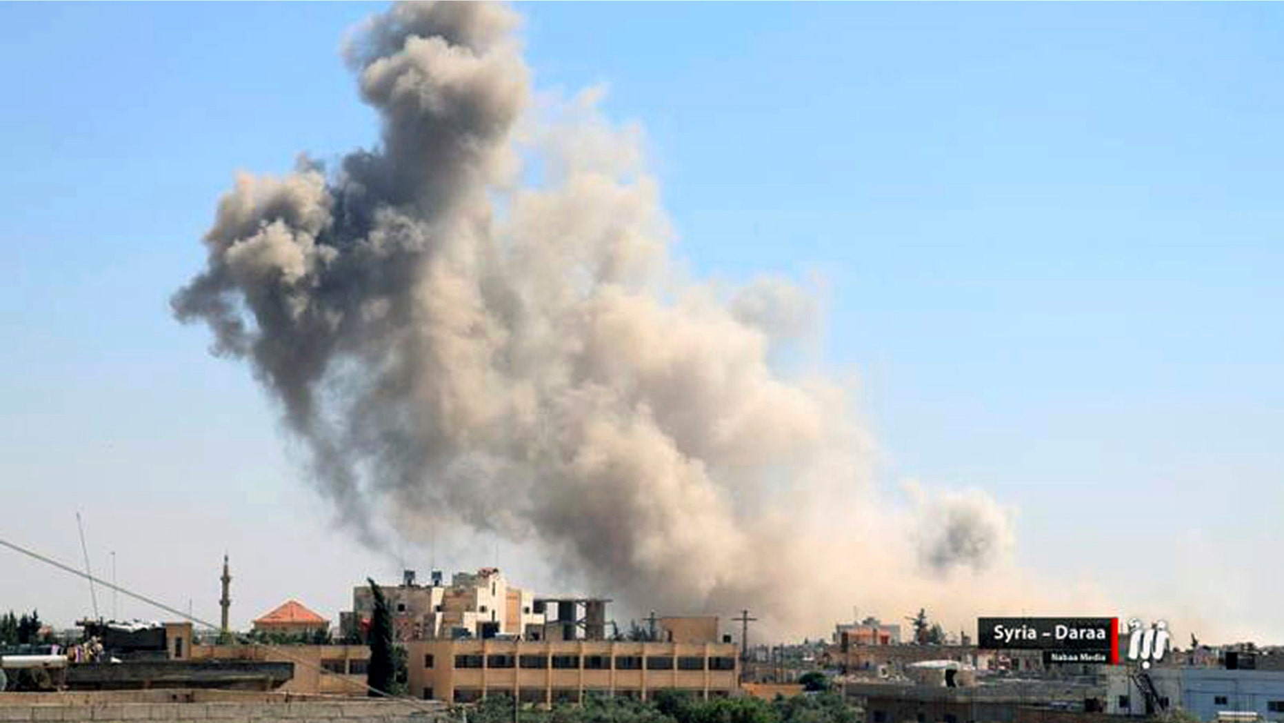 This Tuesday, June 26, 2018 photo provided by Nabaa Media, a Syrian opposition media outlet, shows smoke rising over buildings that were hit by Syrian government forces bombardment, in Daraa, southern Syria.