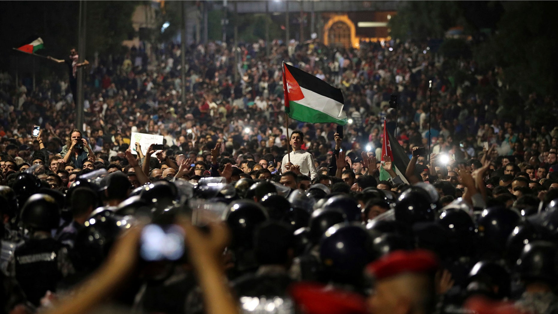 Jordanian protesters shout slogans and raise a national flag during a demonstration outside the Prime Minister's office in the capital Amman early Monday, June 4, 2018.
