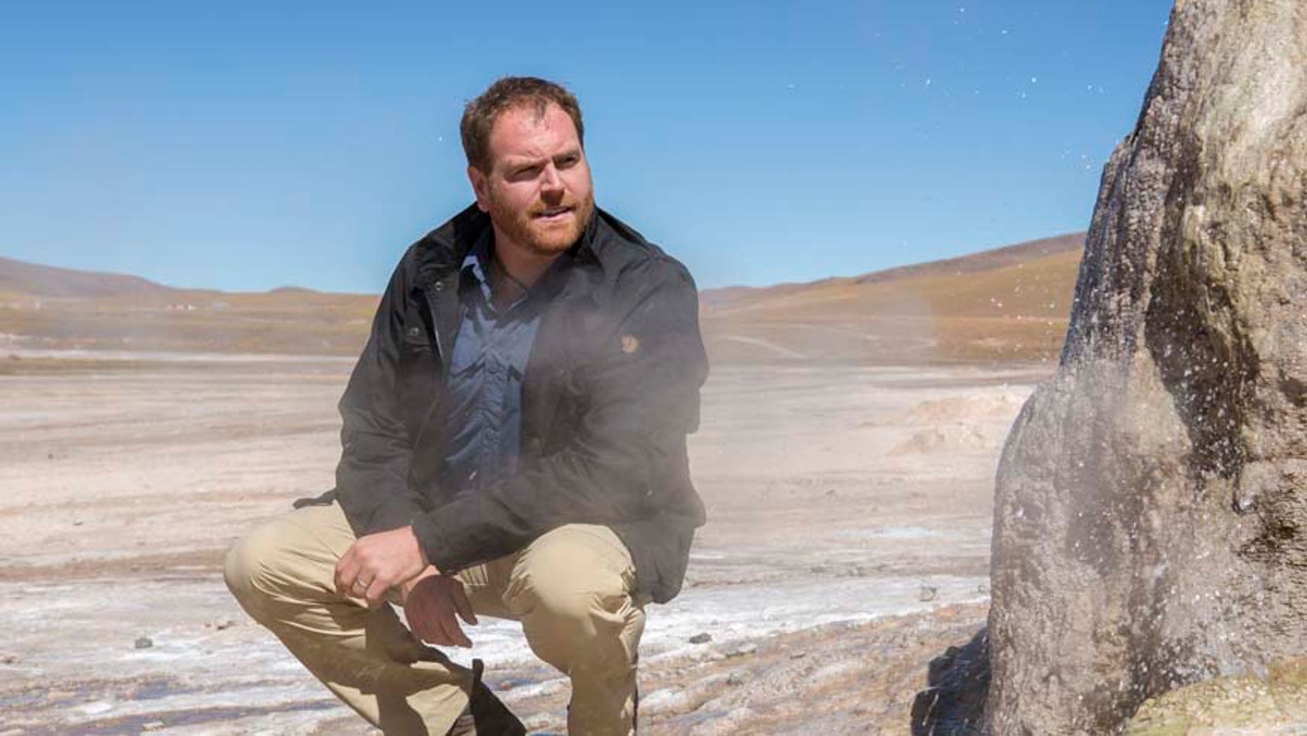 Expedition Unknown host Josh Gates stands next to one of the 80 active geysers of El Tatio Geyser field in the Chilean Andes in the Atacama desert