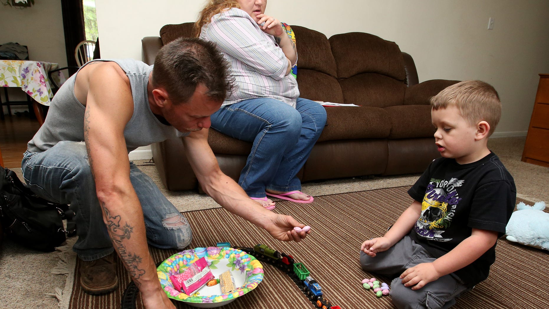 Joshua Sekerak (R) takes a break from playing with his trains to have a piece of candy with his dad Josh as his mom Jennifer looks on at their home in Leetonia, Ohio, United States on May 21, 2016. To match Special Report LEAD-POISONING/TEST-GAPS REUTERS/Aaron Josefczyk - RTSGR6H