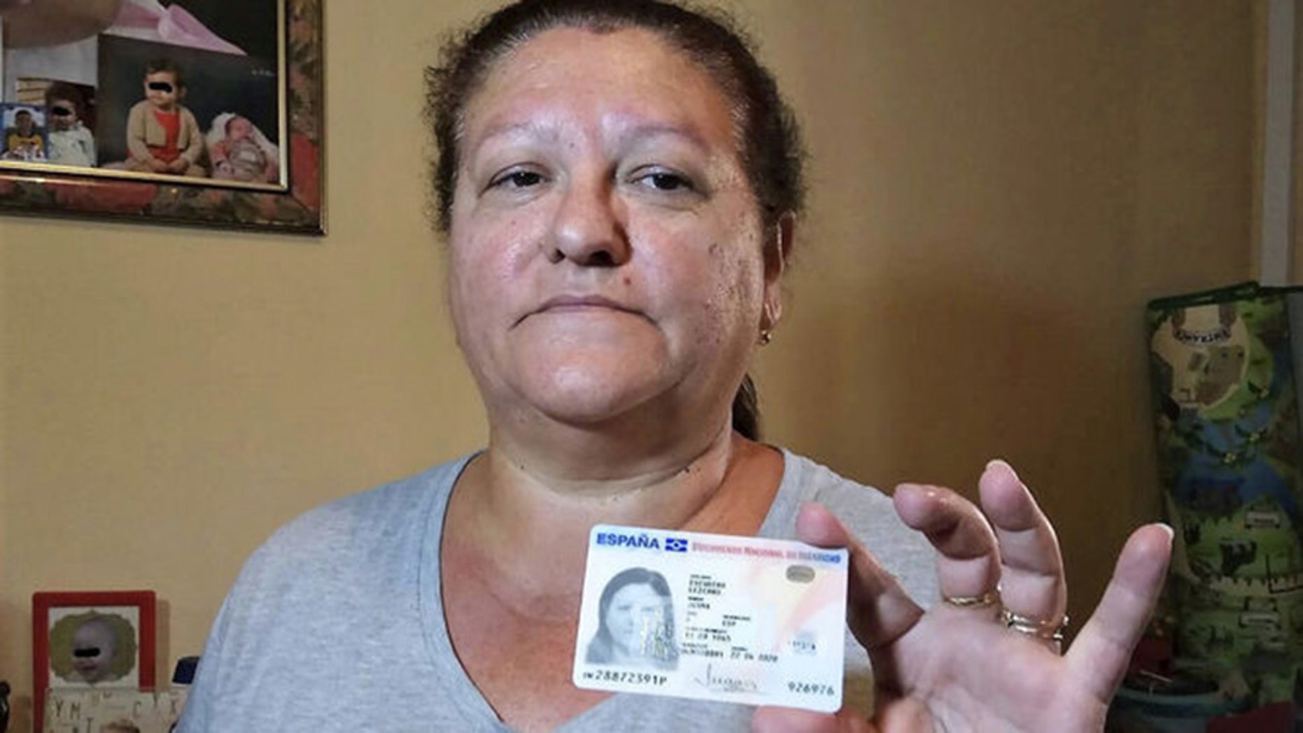 Juana Escudero, holding up her ID card, has a petition for a grave in Malaga, Spain be opened to prove that she is in fact alive.