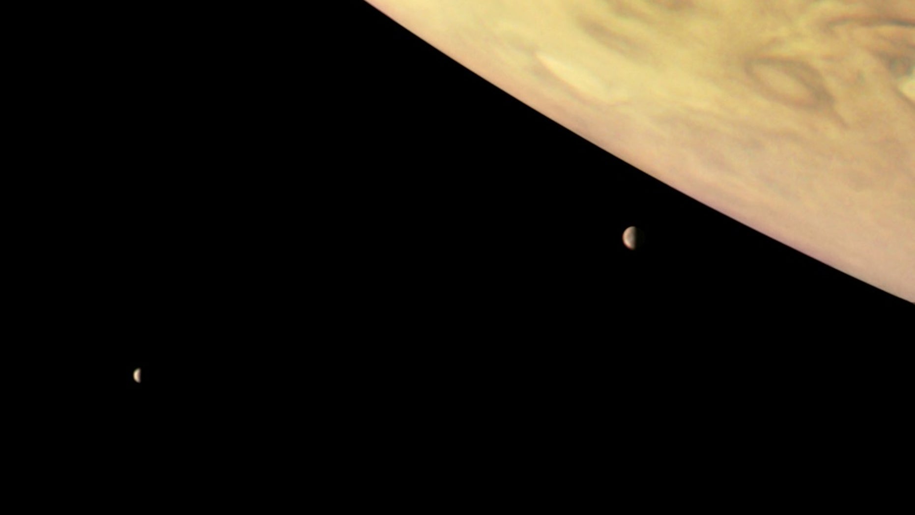 NASA's Juno spacecraft captured this image of Jupiter and two of its biggest moons, Io (right) and Europa (left), on Sept. 1, 2017. This color-enhanced version was processed by citizen scientist Roman Tkachenko using data from the probe's JunoCam imager.