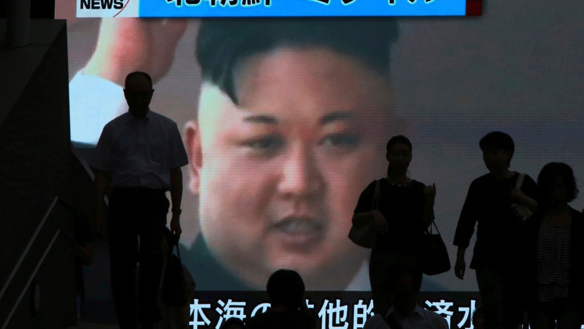 People in Tokyo walk past a TV news showing an image of North Korean leader Kim Jong Un.