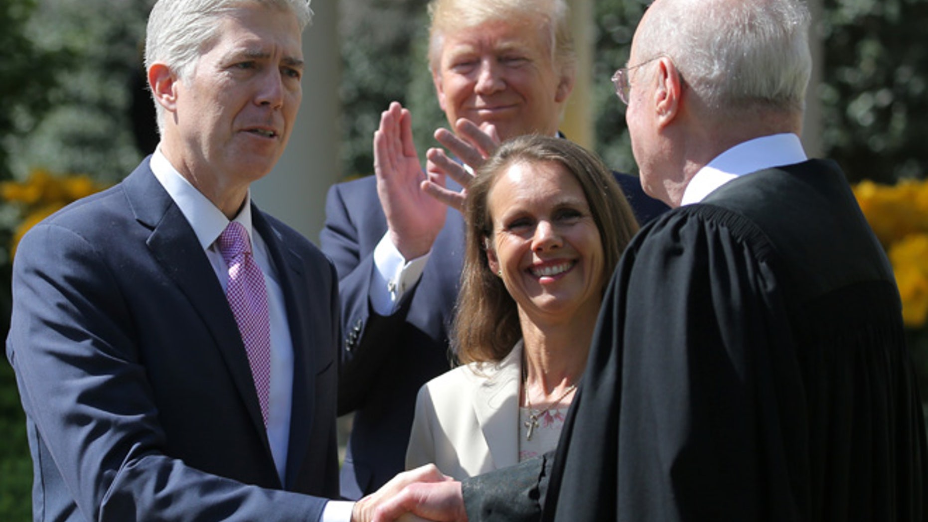 Judge Neil Gorsuch shakes hands with Supreme Court Associate Justice Anthony Kennedy after being sworn in as an Associate Justice of the Supreme Court, accompanied by Louise Gorsuch (C) and U.S. President Donald J. Trump in the Rose Garden of the White House in Washington, U.S., April 10, 2017. REUTERS/Carlos Barria - RTX34YQB