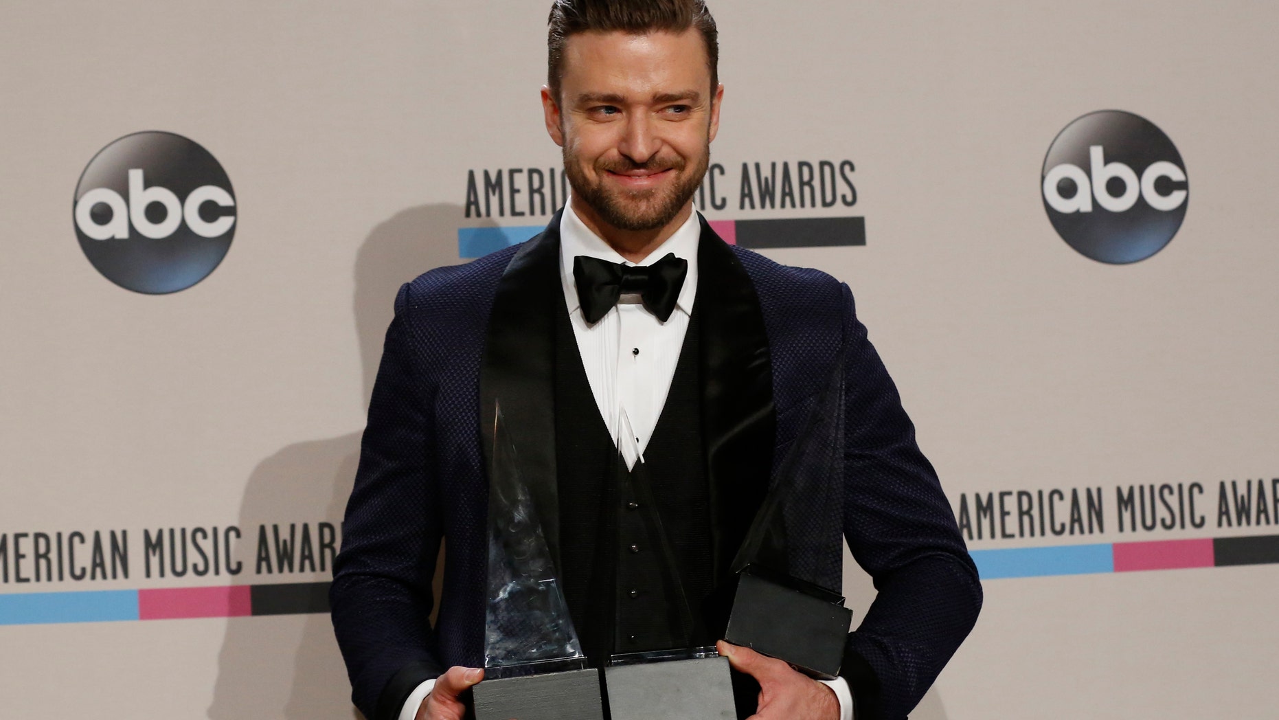November 24, 2013. Musician Justin Timberlake poses backstage with his awards at the 41st American Music Awards in Los Angeles, California.
