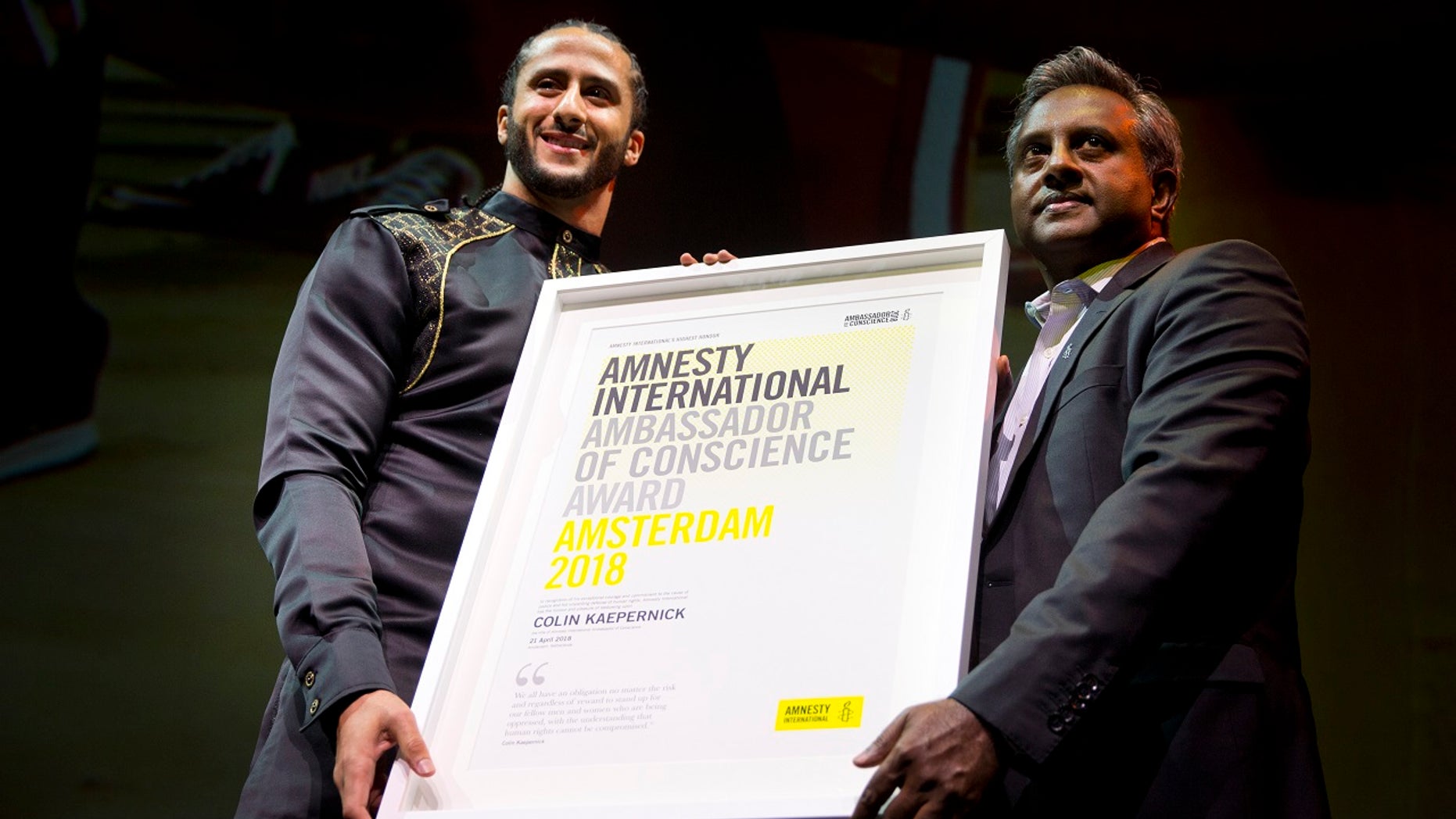 Former NFL quarterback and social justice activist Colin Kaepernick receives the Amnesty International Ambassador of Conscience Award for 2018 from Amnesty International Secretary General Salil Shetty, right, in Amsterdam, April 21, 2018.
