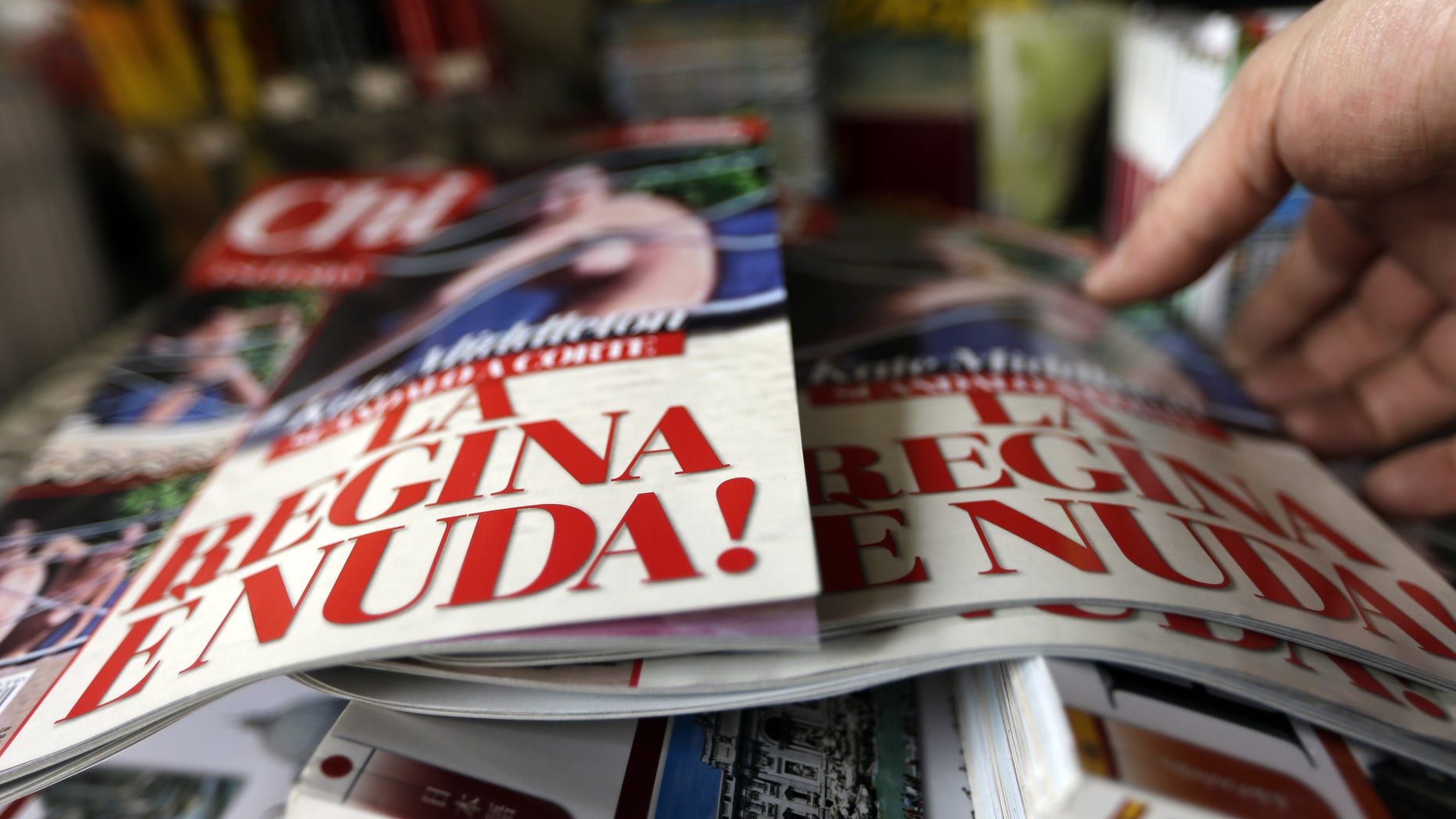 A newstands owner adjusts copies of the Italian magazine Chi reading in Italian "The queen is naked" in Rome, Monday, Sept. 17, 2012. An Italian gossip magazine owned by former Premier Silvio Berlusconi published a 26-page spread of topless photos of Britain's Prince William's wife Kate on Monday despite legal action in France against the French magazine that published them first. Chi hit newsstands on Monday, featuring a montage of photos taken while the Duke and Duchess of Cambridge were on vacation at a relative's home in the south of France last month. They included the 14 pictures published by the popular French magazine Closer, which like Chi is owned by Berlusconi's Mondadori publishing house. (AP Photo/Alessandra Tarantino)