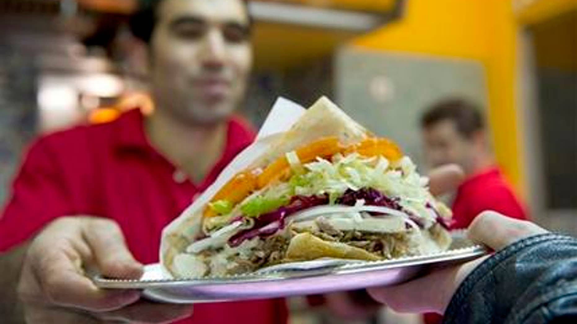 Turkish Abdullah Ekinci serves a doner kebab in a Turkish restaurant in Berlin, Germany, Sunday, March 21, 2010. Forget about bratwurst, currywurst and other kinds of sausages _ doner kebab, or shawarma, has overtaken traditional German fast food as the country's favorite snack on the go. (AP Photo/Gero Breloer)