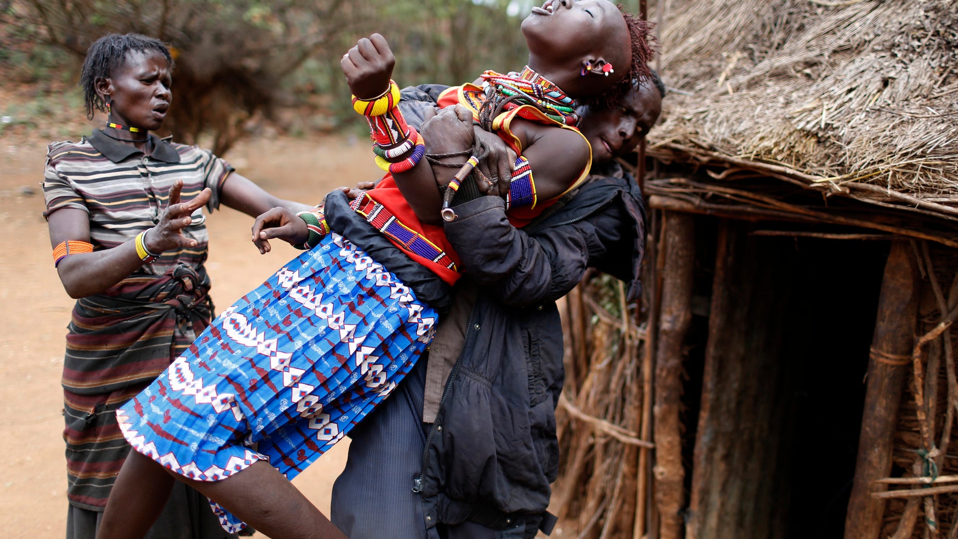 A man holds a girl as she tries to escape when she realised she is to to be married, about 80 km (50 miles) from the town of Marigat in Baringo County December 7, 2014. REUTERS/Siegfried Modola
