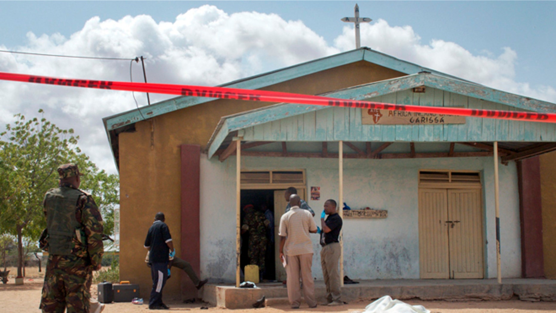 July 1, 2012: Members of the Kenyan security forces inspect the scene, as a body lies covered by a sheet, outside the African Inland Church in Garissa, Kenya.