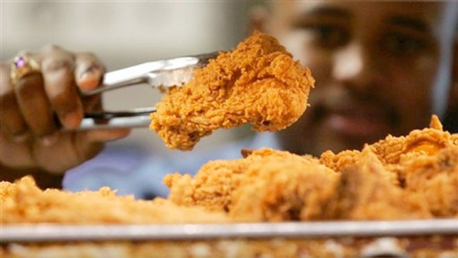 FILE: A Kentucky Fried Chicken employee uses tongs to hold up an sample of the company's trans fat-free Extra Crispy fried chicken in New York.