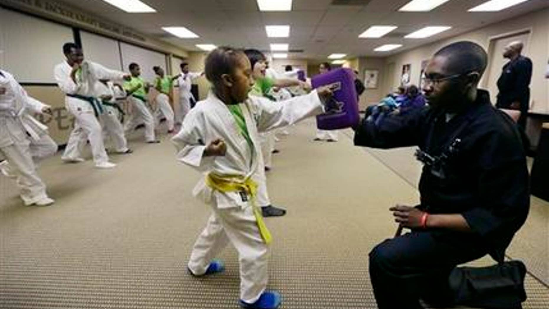 Jan. 28, 2015: In a photo in Southfield, Mich. Jayson Harris punches a pad held by Michael Hunt during the Kids Kicking Cancer class.