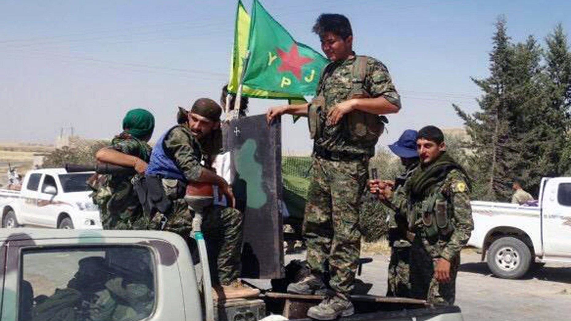 In this file photo released on Tuesday, June 23, 2015, provided by the Kurdish fighters of the People's Protection Units (YPG), which has been authenticated based on its contents and other AP reporting, Kurdish fighters of the YPG, sit on their pickup in the town of Ein Eissa, north of Raqqa city, Syria.