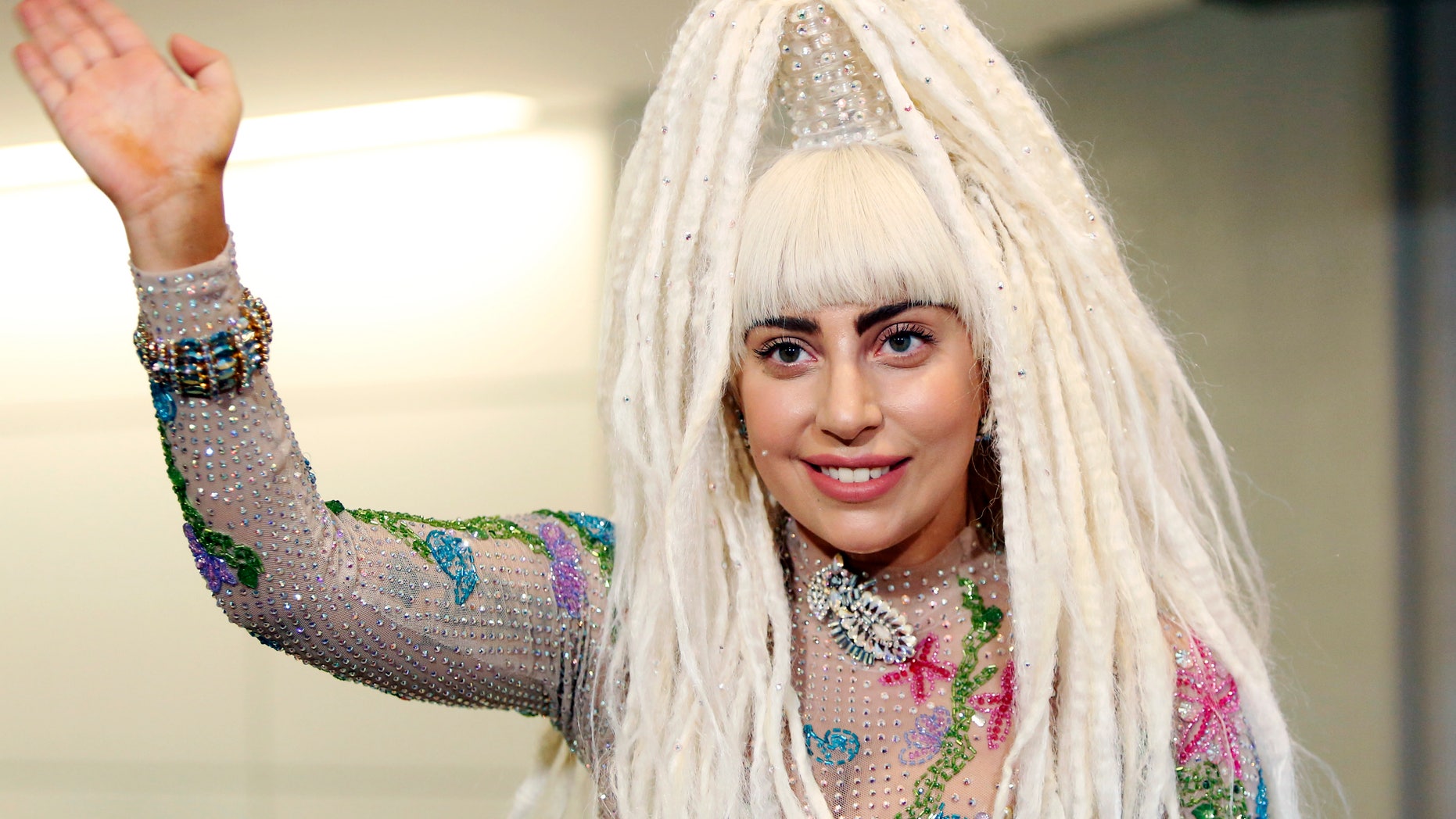 August 12, 2014. Singer Lady Gaga waves upon her arrival at Narita international airport, east of Tokyo.