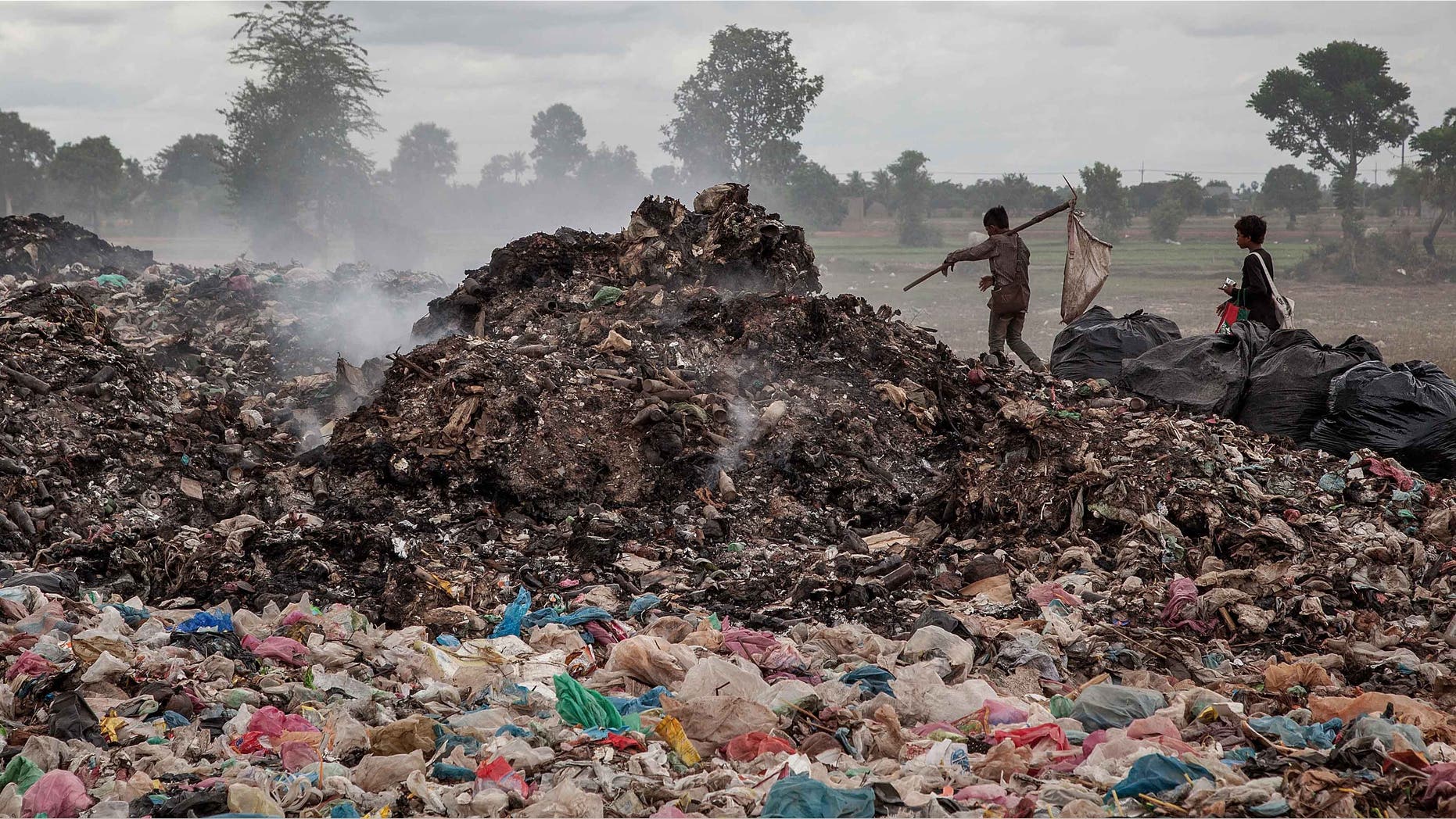 SIEM REAP, CAMBODIA - JUNE 11: A couple of young boys walk between tons of rubbish where they work daily in the Anlong Pi landfill on June 11, 2014 in Siem Reap, Cambodia. Dozens of children work every day in the Anlong Pi landfill, which is situated only few kilometres aways from the world famous Angkor temples, visited by more than 3 million tourists every year. Despite the Cambodian government's commitments and legal responsibilities to end child labor - enshrined in its ratification of relevant international covenants, domestic laws and the implementation of several national policies aimed at ending child labor - it remains a significant concern in Cambodia, where almost a third of the population lives on less than a dollar per day. Child labor is a consequence of this poverty, often resulting from a family's inability to support itself. According to a recent report from the International Labour Organisation (ILO), an estimated 19.1% of the close to 4 million children in Cambodia between the ages of 5 and 17 engage in economic activities. An estimated 56.9% of those children are child labourers, with a third of them being involved in hazardous activities mostly in the agriculture, forestry and fishing sectors. (Photo by Omar Havana/Getty Images)
