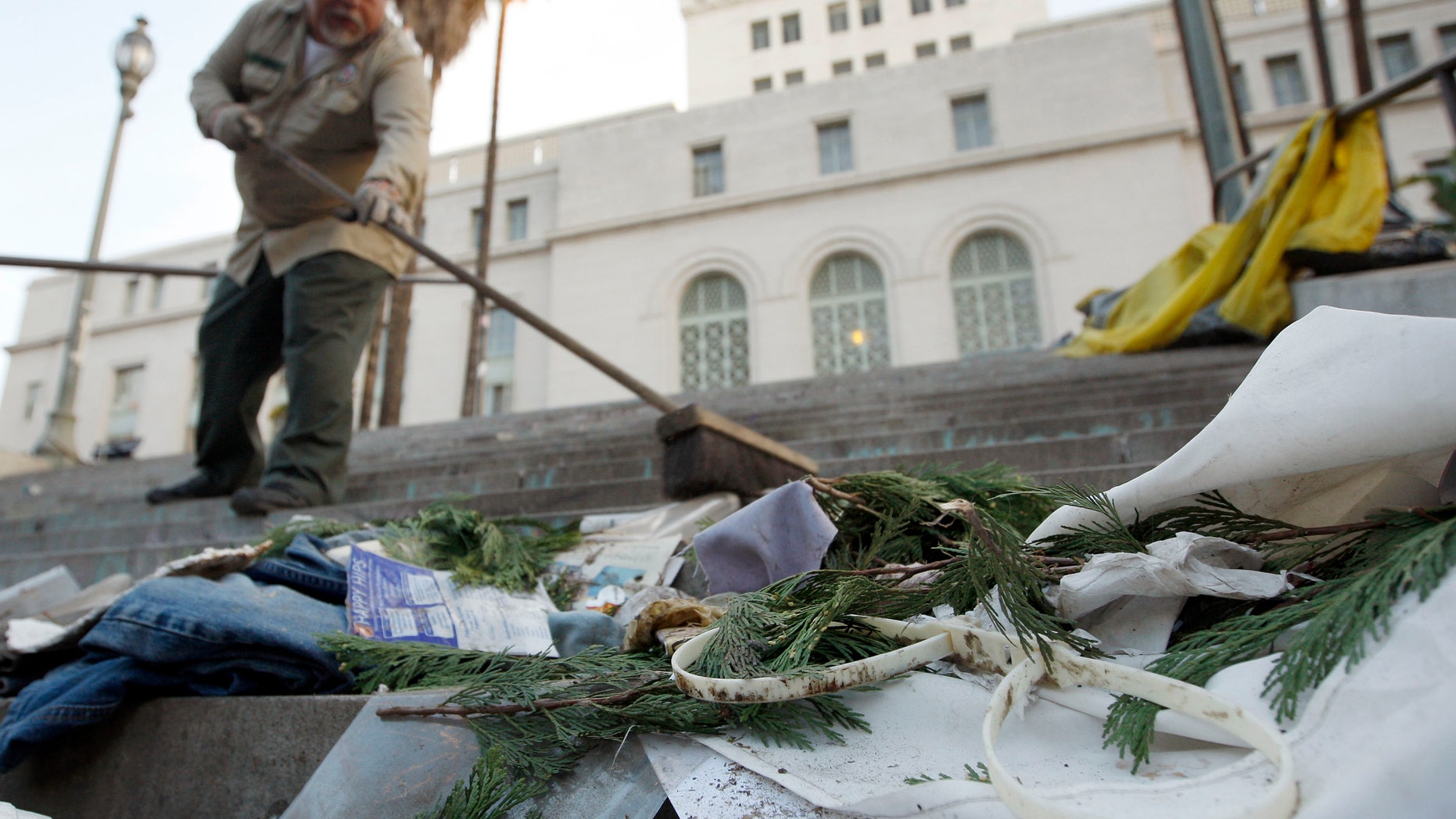 Nov. 30, 2011: City sanitation worker Gino Rodriguez sweeps plastic police handcuffs and other debris from the south steps of City Hall at the Occupy Los Angeles encampment at City Hall Park.