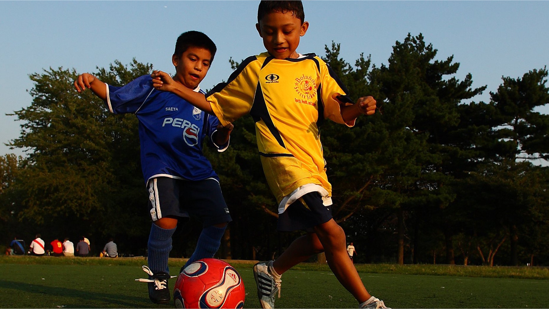 QUEENS, NY - SEPTEMBER 7: Boys play a pickup game of soccer as their adult relatives participate in the Fedeiguayas Soccer League on September 7, 2007 at Flushing Meadows Park in the Queens Borough of New York. A large Hispanic population from Mexico, Central and South America now living in New York congregate to this park every weekend to play soccer, and relax with family and friends. They play on ten soccer fields throughout the park and play goes from early morning till dusk. The participants are highly skilled semi pro level players and each team dresses in the colors of their country and play as if it was their own World Cup. Matches are very competitive as the pride of each team's country is on the line. (Photo by Al Bello/Getty Images)