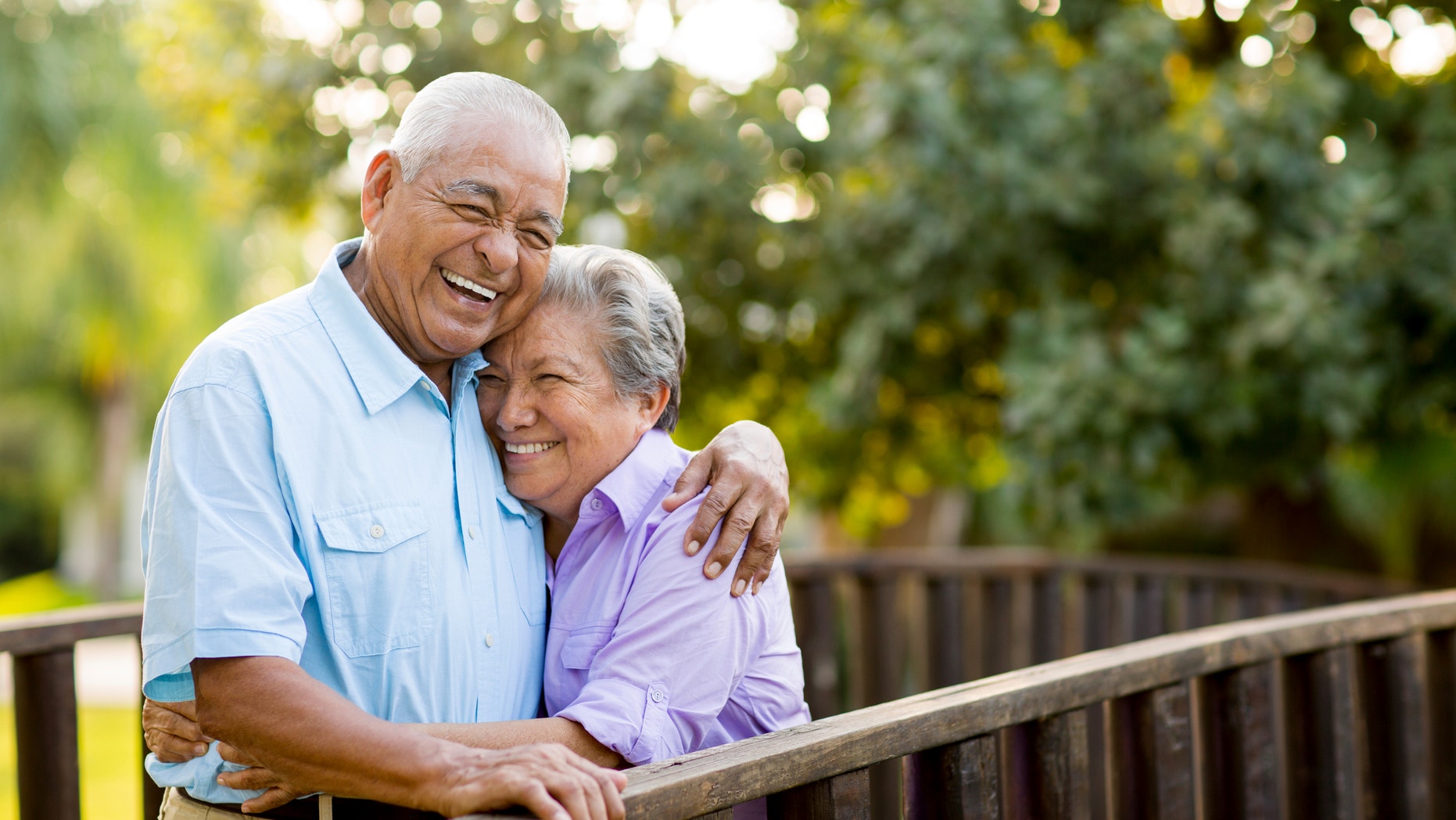 A mexican senior couple laughing together on bridge.