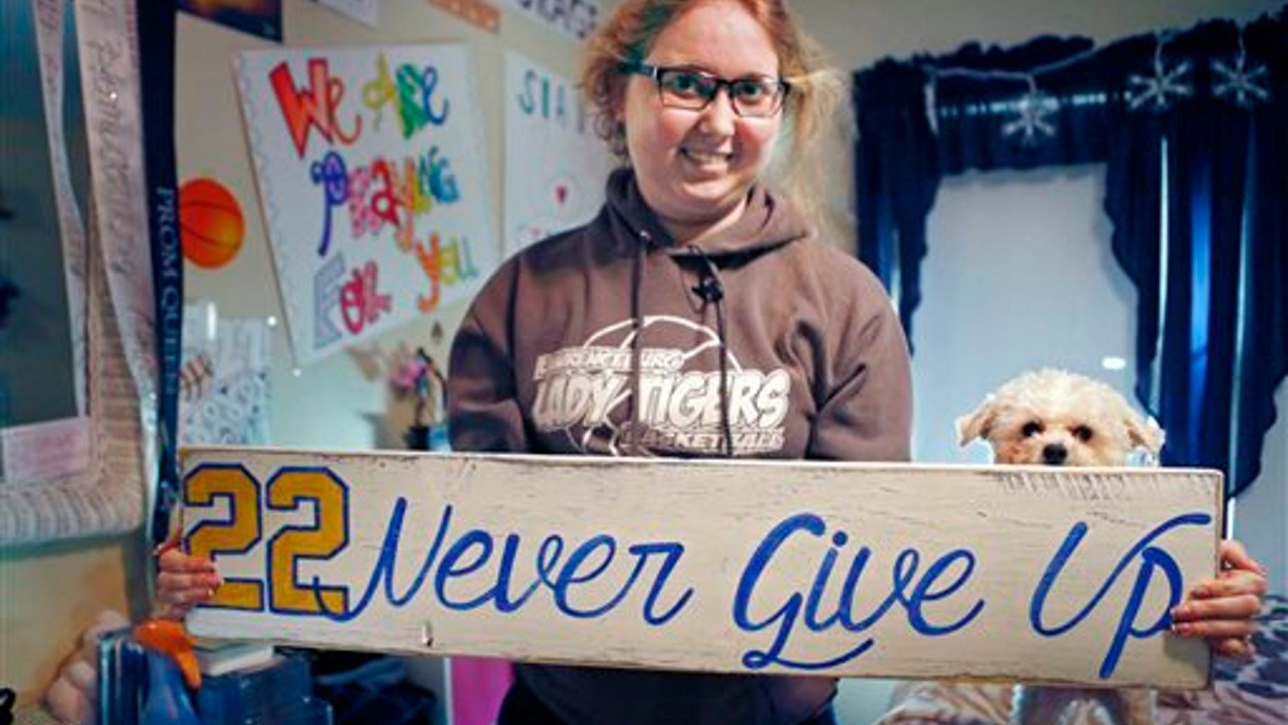 In this Dec. 8, 2014, file photo, Lauren Hill holds a sign made for her, which she keeps in her room in Cincinnati, along with many other messages and gifts of support. (AP Photo/The Enquirer, Carrie Cochran, File)