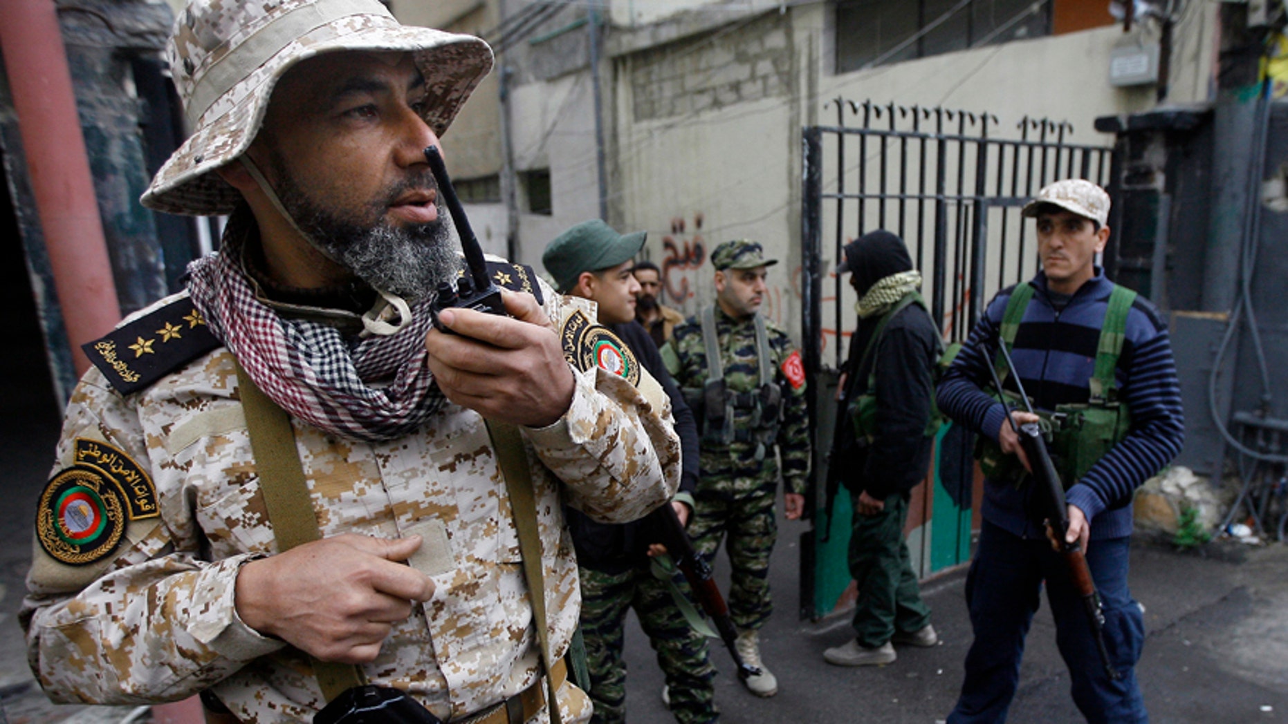A Palestinian officer from the Fatah movement, speaks on a walkie talkie as others hold their weapons in the Ein el-Hilweh refugee camp, in the southern port city of Sidon, Lebanon, Wednesday, March. 1, 2017. The U.N. says it is suspending services in the conflict-torn Ein el-Hilweh Palestinian camp in south Lebanon for the third straight day. At least eight civilians, including a thirteen year old boy and a UN staffer, have been wounded in the latest round of violence to consume the camp, according to a statement released jointly by the U.N.'s child relief and Palestinian relief agencies, on Tuesday. (AP Photo/Mohammed Zaatari)