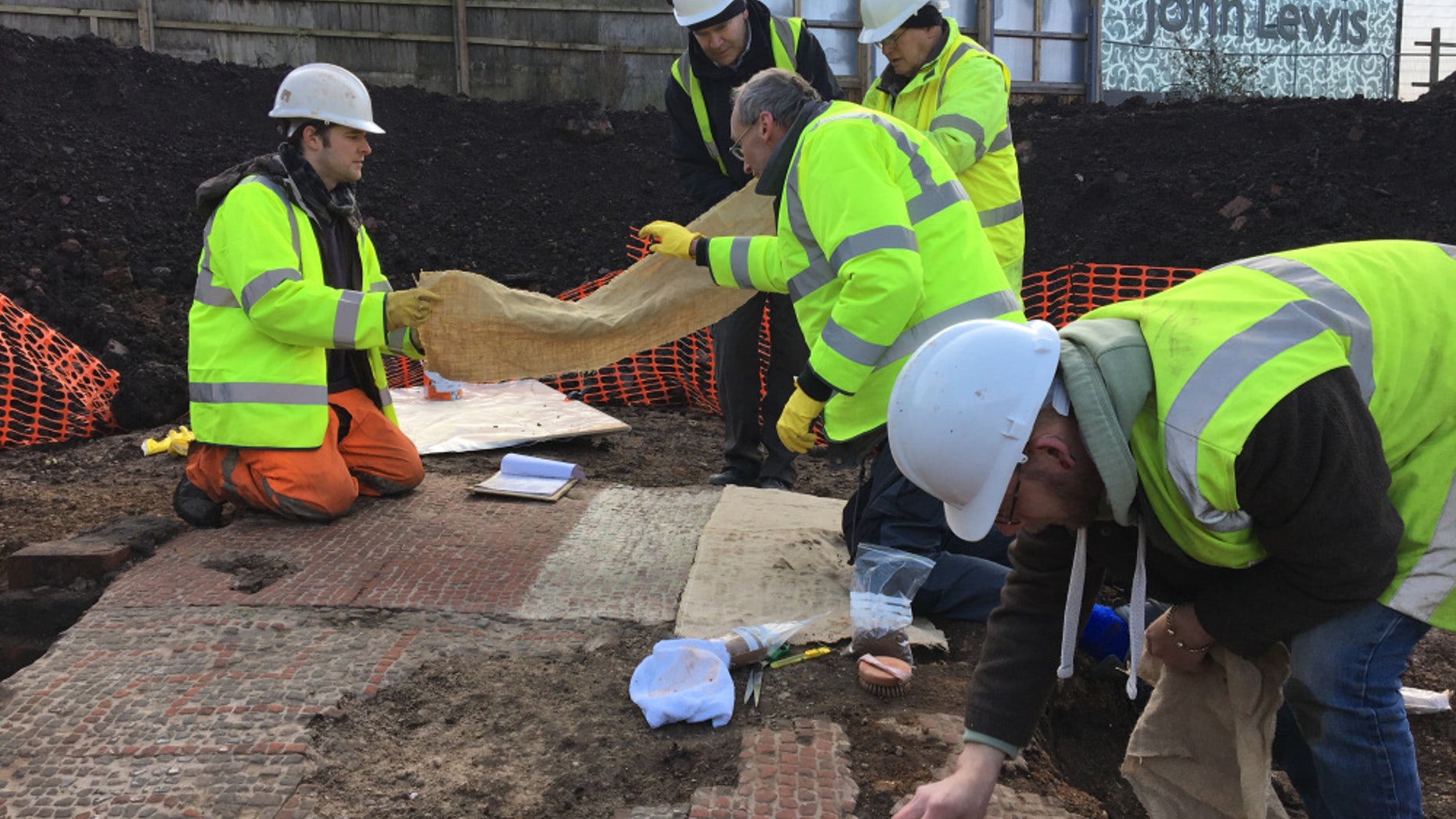 The team of conservators and archaeologists carefully prepare to lift the mosaic. (ULAS)