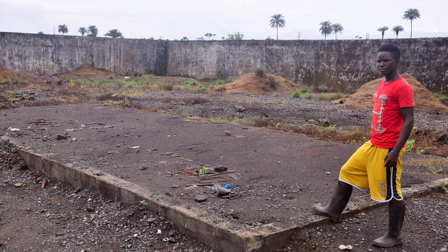 In this photo taken Saturday, March 26, 2015, a boy, stands next to a place that was used to stack bodys of Ebola victims at a crematorium in Boys Town on the outskirts of Monrovia, Liberia.