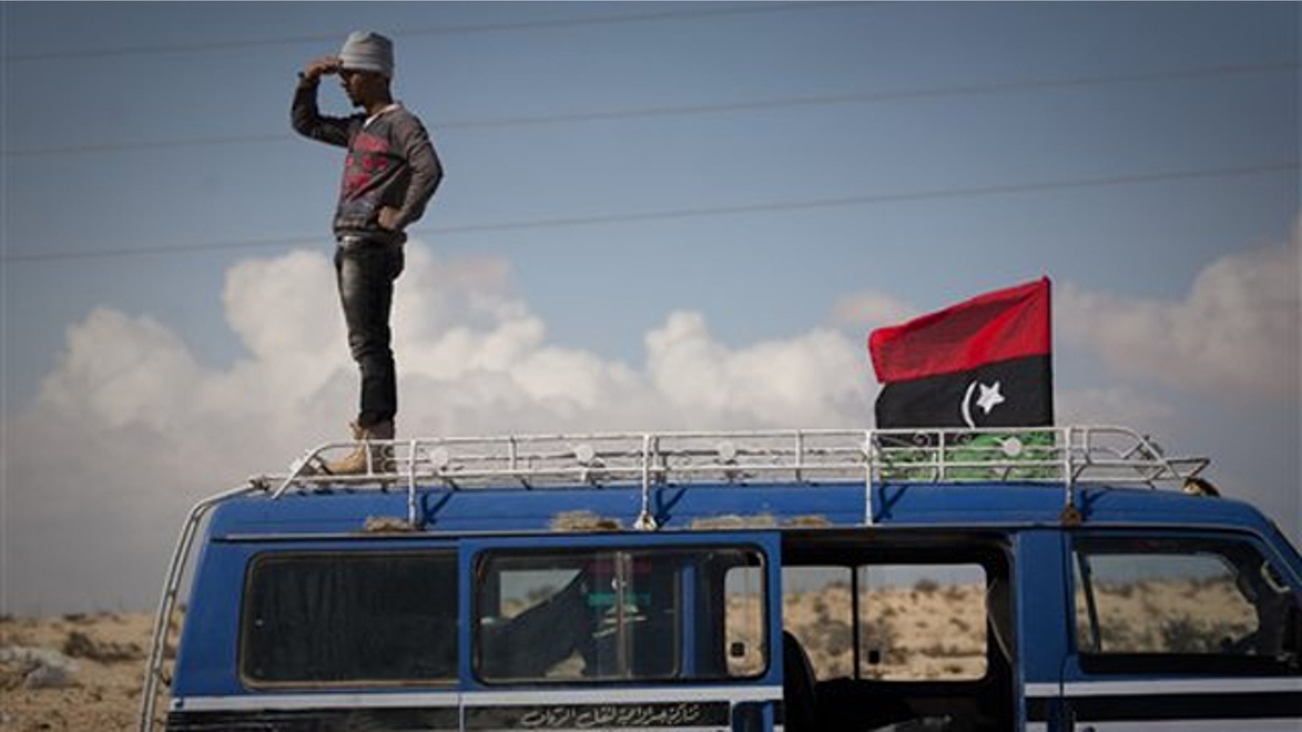 A Libyan man stands on top of his car looking at the frontline of fighting between rebels and Muammar al-Qaddafi's forces outside the city of Ajdabiya in eastern Libya March 22.