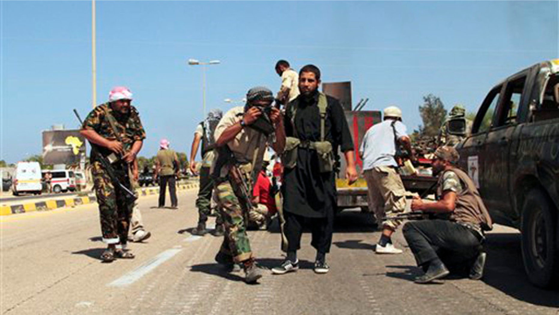 Revolutionary fighters take cover from heavy artillery, rocket and missile counter-attacks launched by Qaddafi loyalists in Sirte, Libya, Saturday, Sept. 24, 2011