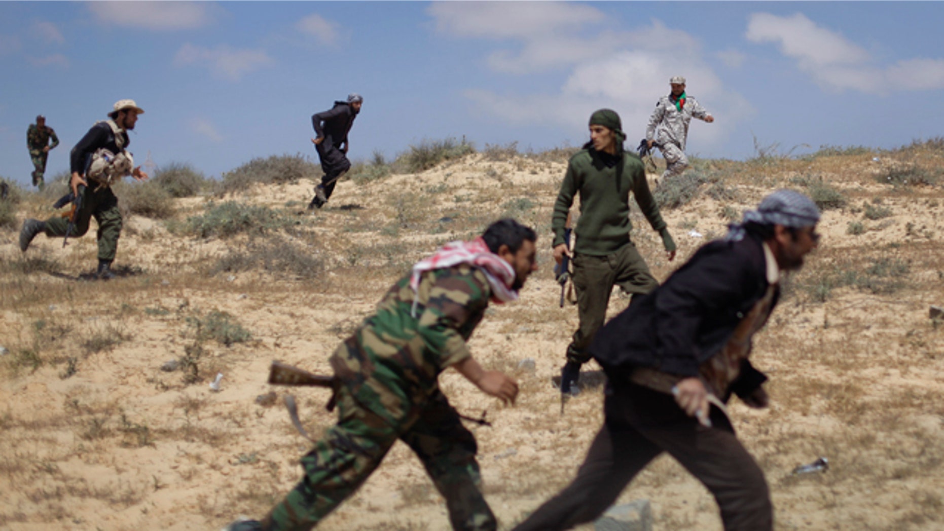 April 4: Rebel fighters run for cover from incoming shelling by pro-Qaddafi forces, near the front line in Brega, Libya. Libyan rebels pushed into the strategic oil town of Brega on Monday but came under fire from Muammar Qaddafi's forces, as a government envoy began a diplomatic push in Europe to discuss an end to the fighting. (AP)