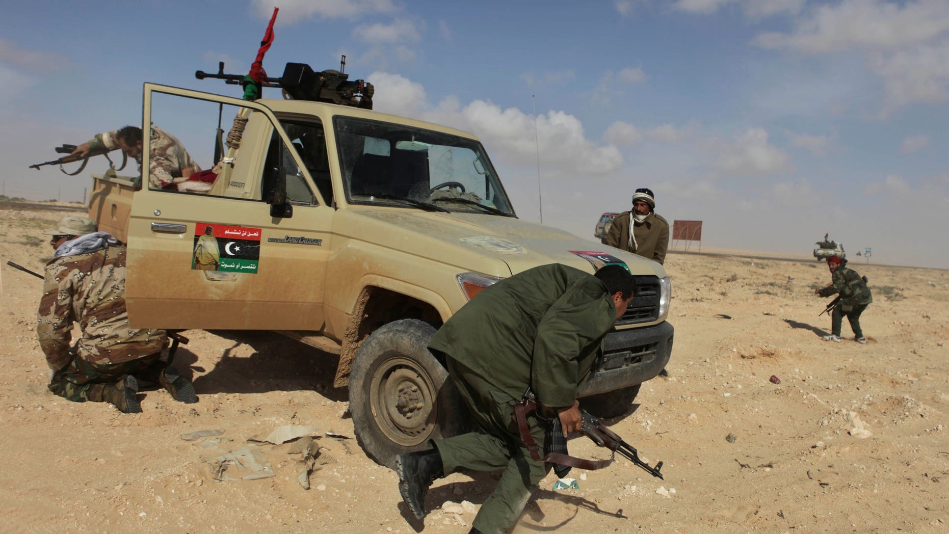 Libyan rebels run for cover after coming under heavy artillery fire from pro-Qaddafi forces along the front line near Brega, Libya, Friday, April 1, 2011. Libya's rebels will agree to a cease-fire if Muammar al-Qaddafi pulls his military forces out of cities and allows peaceful protests against his regime, an opposition leader said Friday as rebels showed signs that their front-line organization is improving