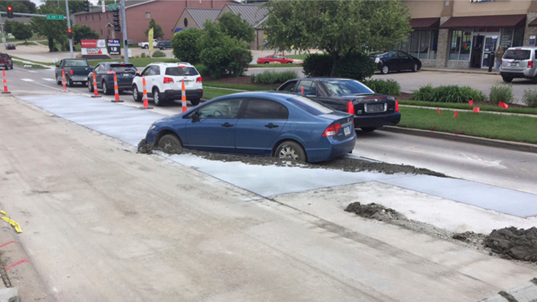 A Honda driven by a 19-year-old driver is stuck in the newly poured concrete in Lincoln, Neb., Wednesday.