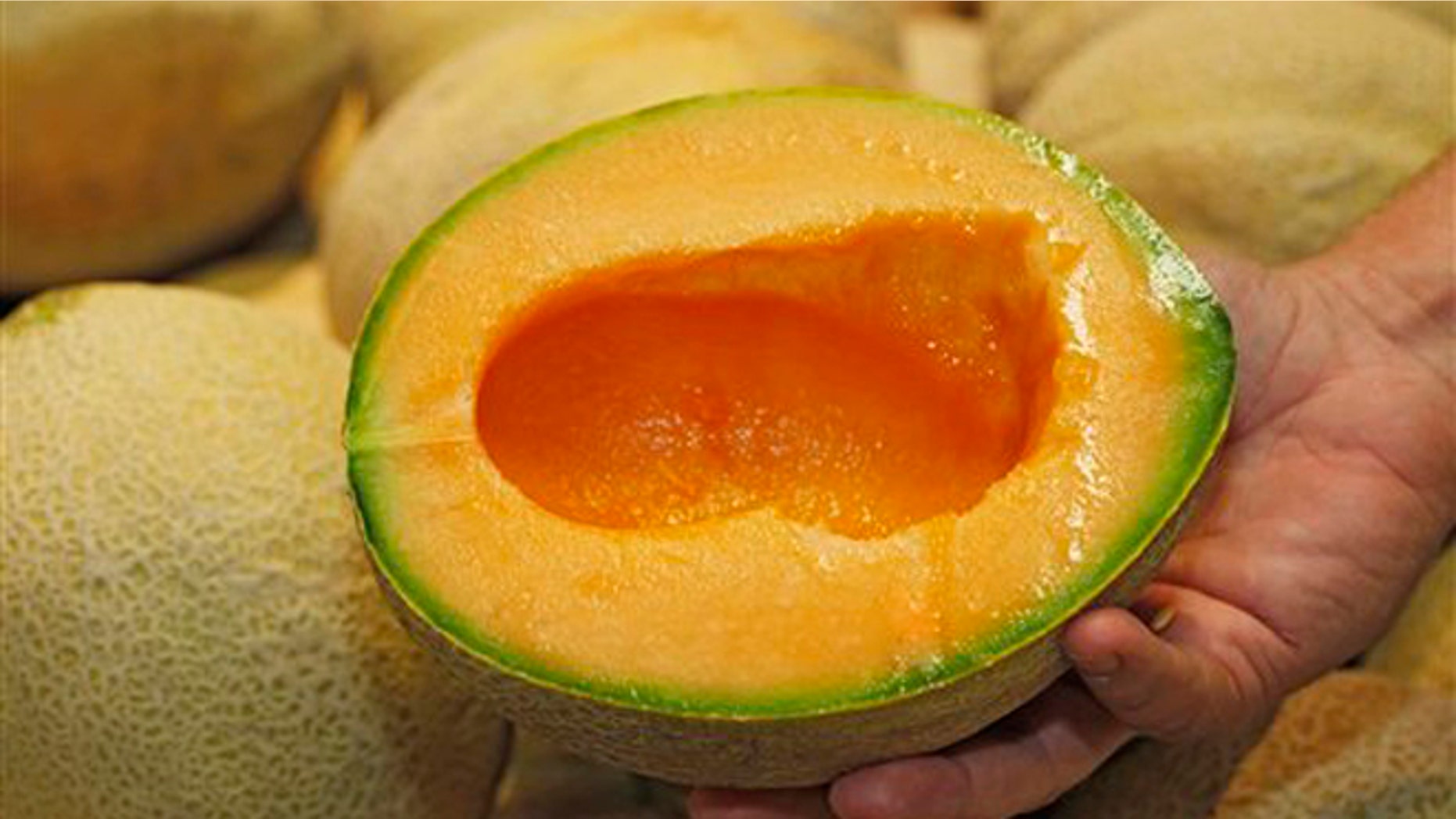 July 13, 2012: Produce manager Nate Codina holds a cut Rocky Ford cantaloupes at a Denver Kings Soopers market.