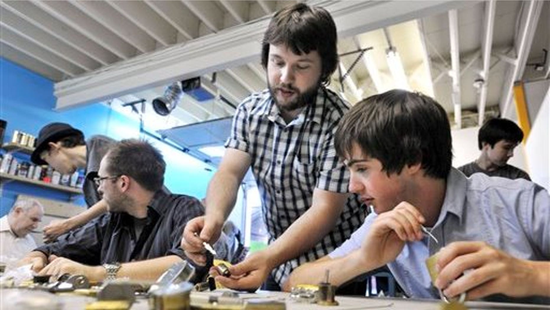 July 2: competitive lockpicker Schuyler Towne, center, teaches Alex Kalamaroff, right, about a type of lock during a competitive lockpicking class. in Somerville, Mass. (AP)